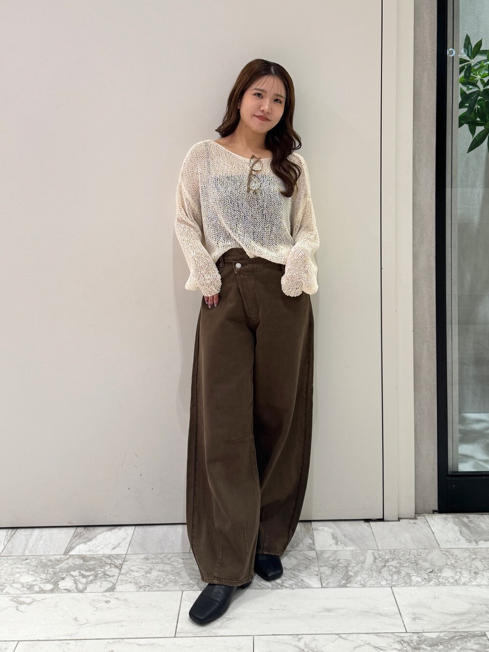 ブラウン系のデニムパンツ、ホワイト系のニット/セーター、ブラック系のサンダルを着用したレディースの秋コーディネートの2枚目の写真