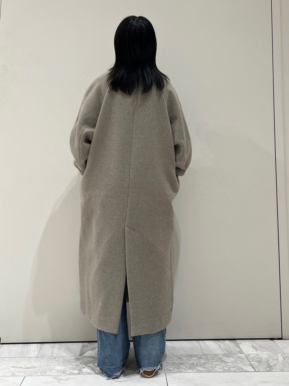 グレー系のチェスターコート、イエロー系のニット/セーター、ブルー系のデニムパンツを着用したレディースの秋コーディネートの8枚目の写真