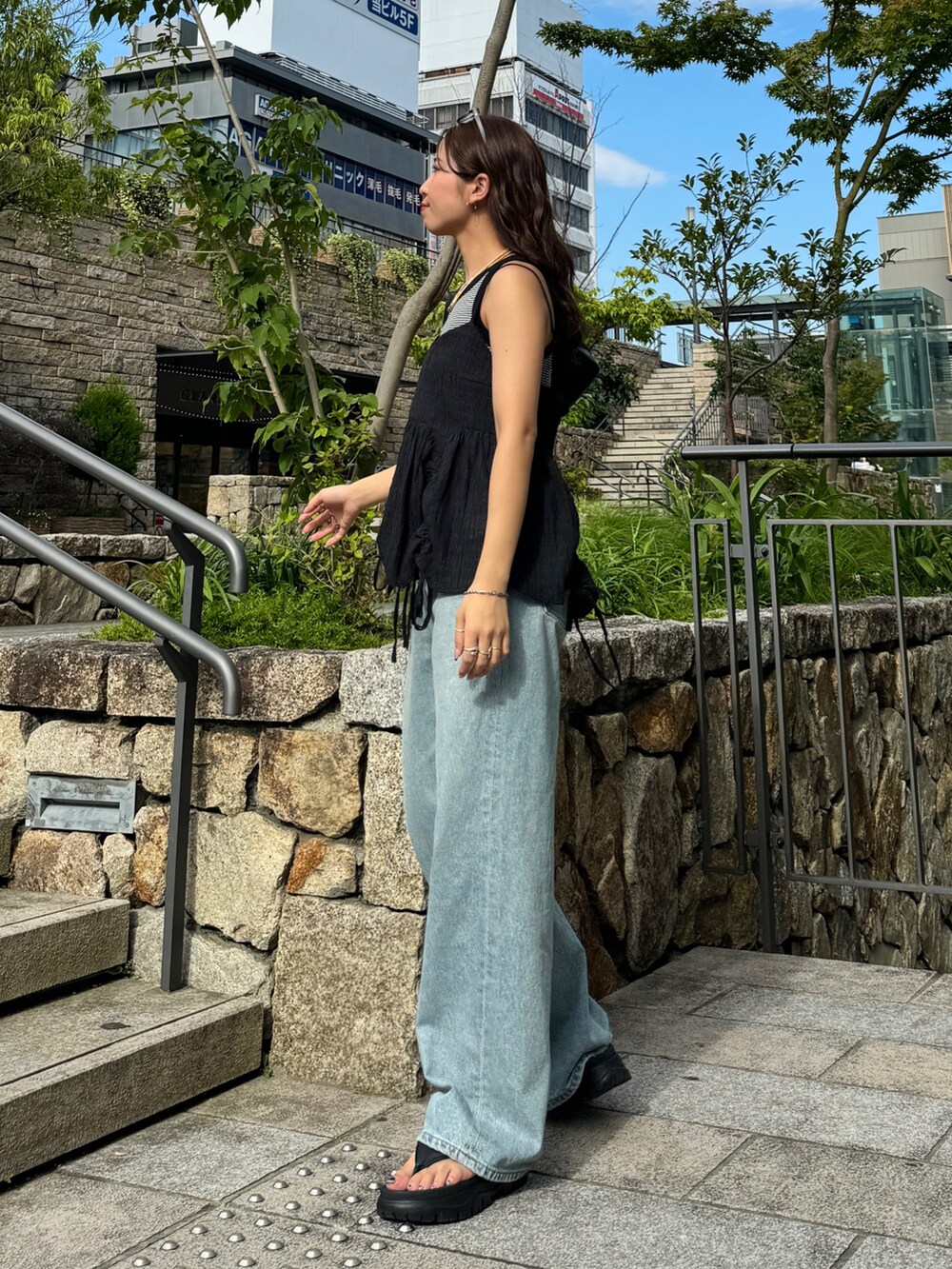 グレー系のタンクトップ、ブラック系のシャツ/ブラウス、ブルー系のデニムパンツを着用したレディースの夏コーディネートの2枚目の写真