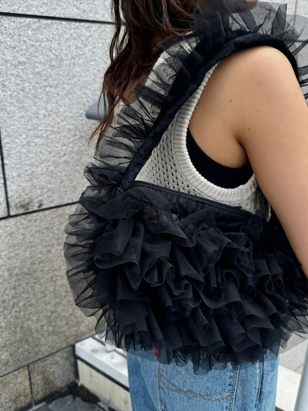 ブルー系のデニムパンツ、ホワイト系のニット/セーター、ブラック系のショルダーバッグを着用したレディースの秋コーディネートの9枚目の写真