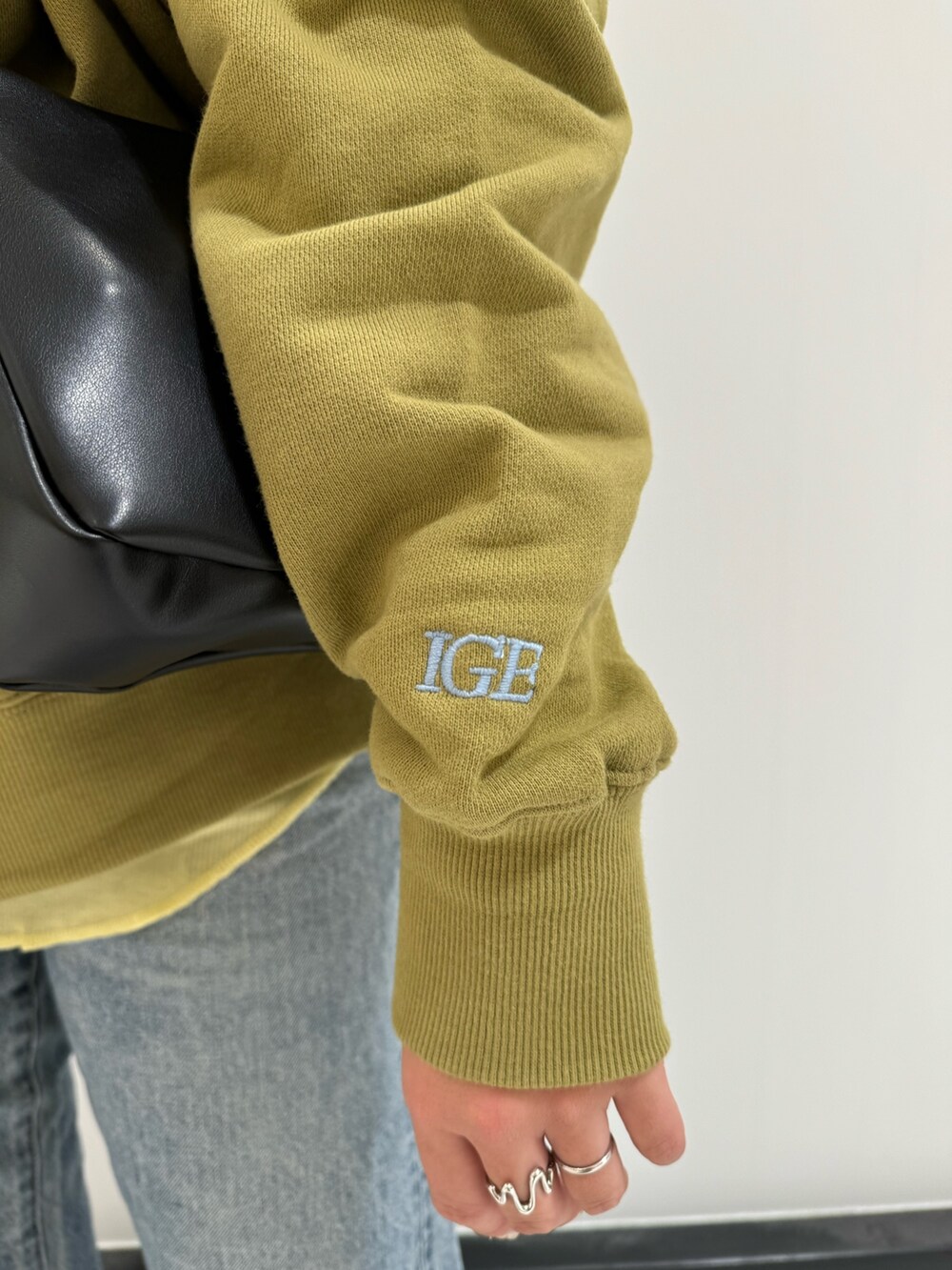 グリーン系のスウェット、ブラック系のショルダーバッグ、イエロー系のTシャツ/カットソーを着用したレディースの冬コーディネートの7枚目の写真