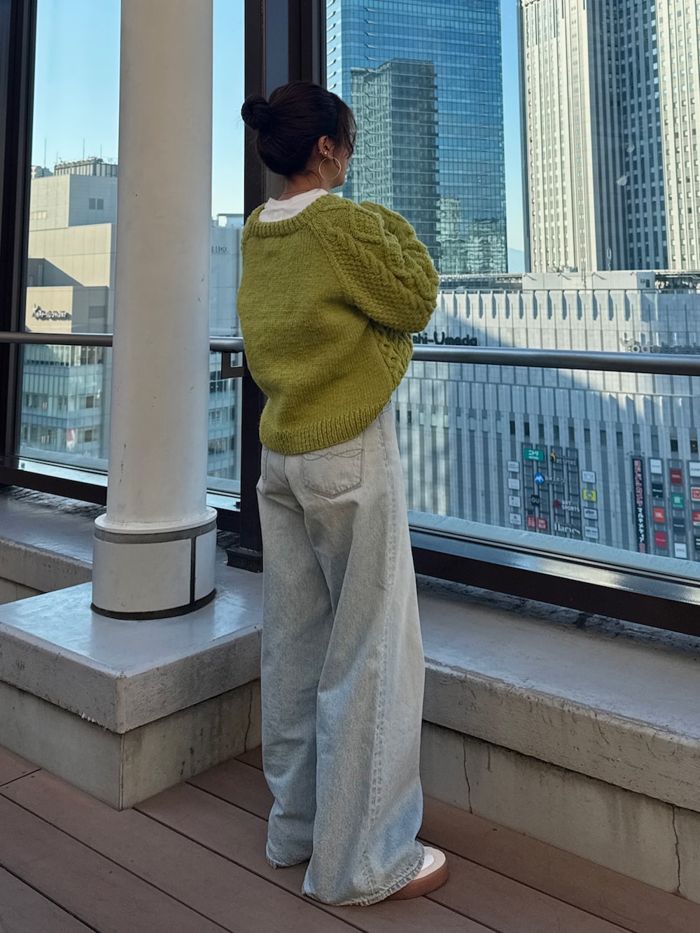 グリーン系のニット/セーター、ホワイト系のTシャツ/カットソー、ブルー系のデニムパンツを着用したレディースの冬コーディネートの6枚目の写真
