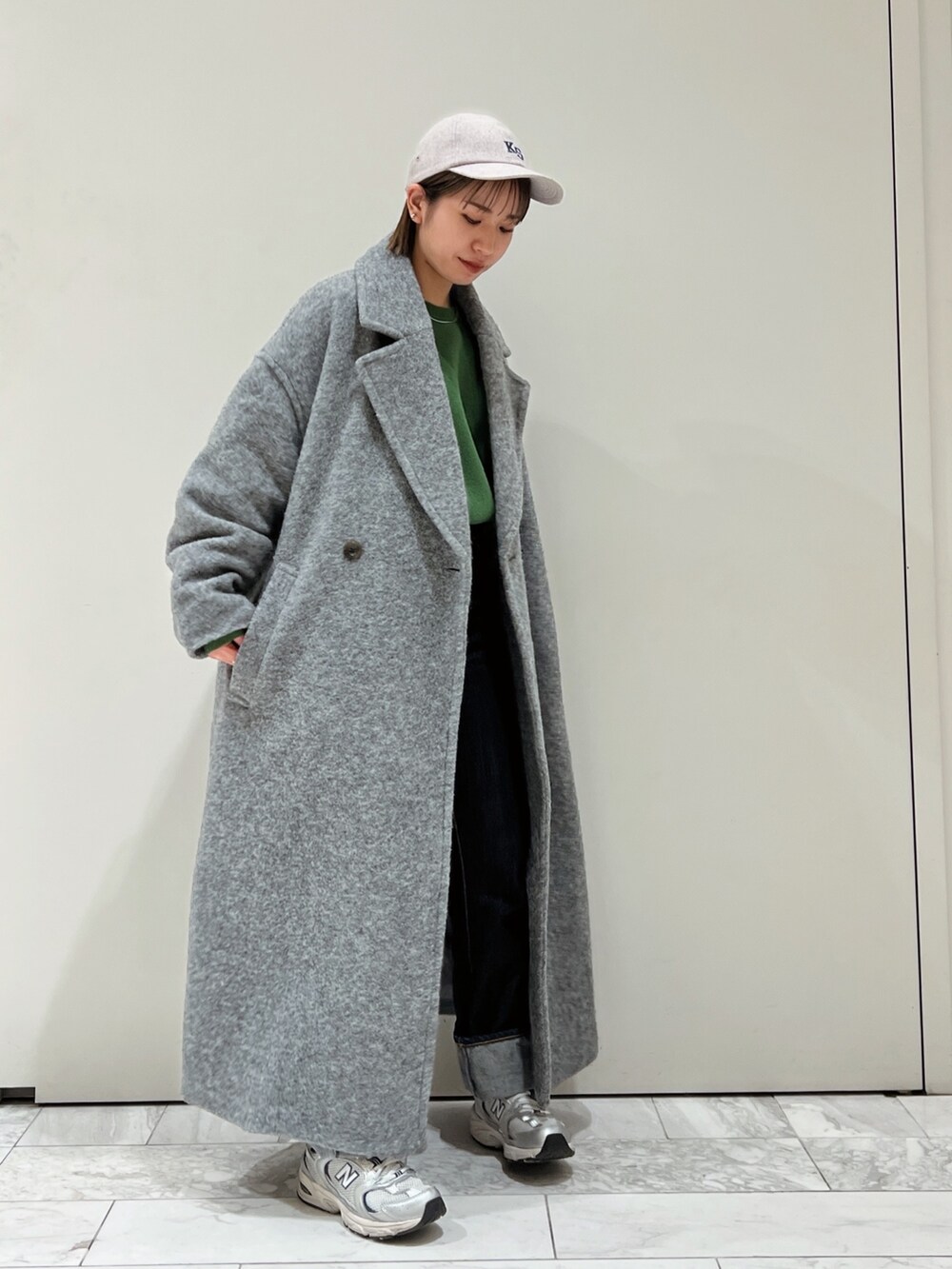 グレー系のチェスターコート、グリーン系のニット/セーター、グレー系のキャップを着用したレディースの冬コーディネートの4枚目の写真