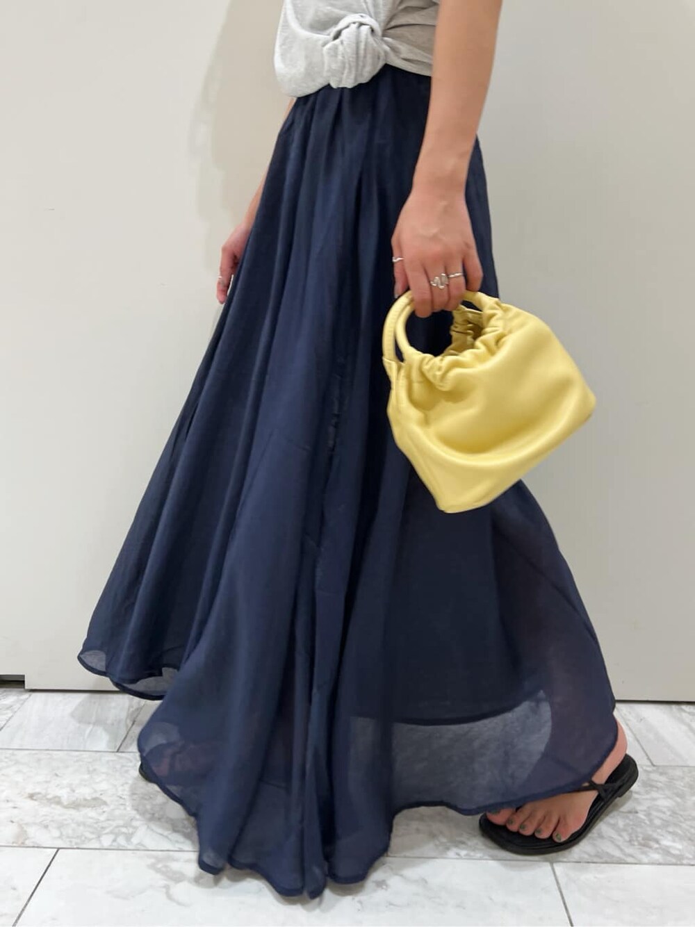 ブラック系のサンダル、ブルー系のスカート、イエロー系のハンドバッグを着用したレディースの春コーディネートの8枚目の写真