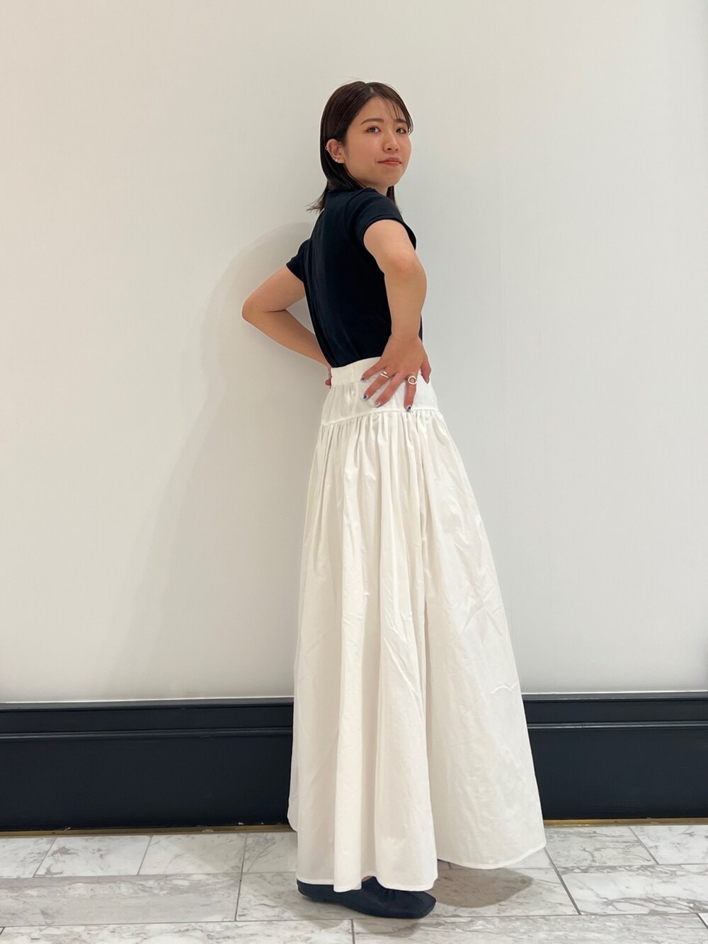 ホワイト系のスカート、ブラック系のTシャツ/カットソー、ブラック系のパンプスを着用したレディースの春コーディネートの5枚目の写真