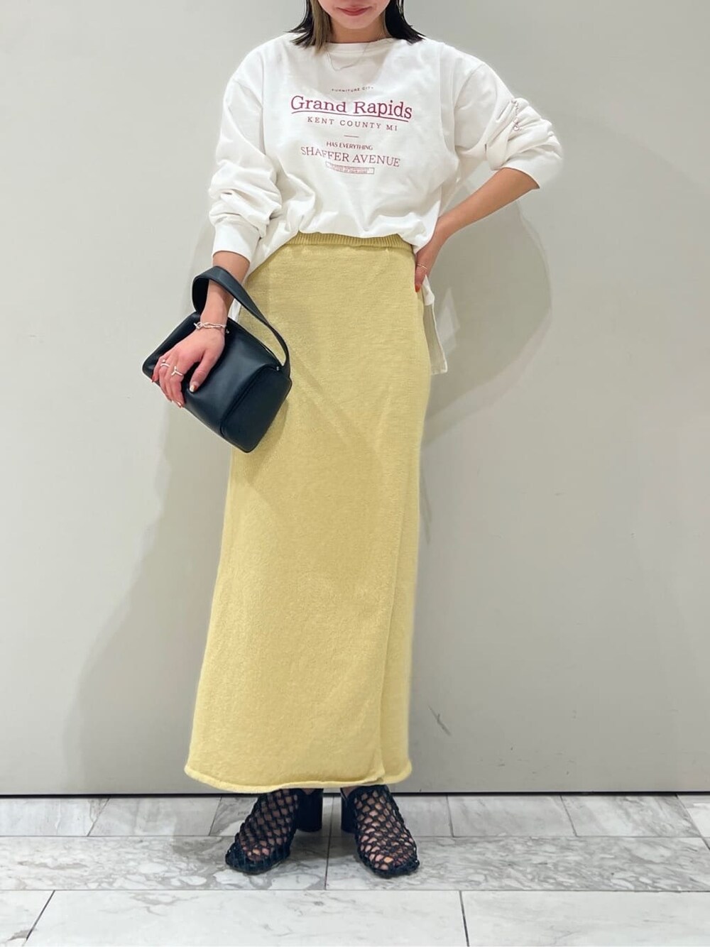ブラック系のハンドバッグ、イエロー系のスカート、ホワイト系のTシャツ/カットソーを着用したレディースの春コーディネートの5枚目の写真