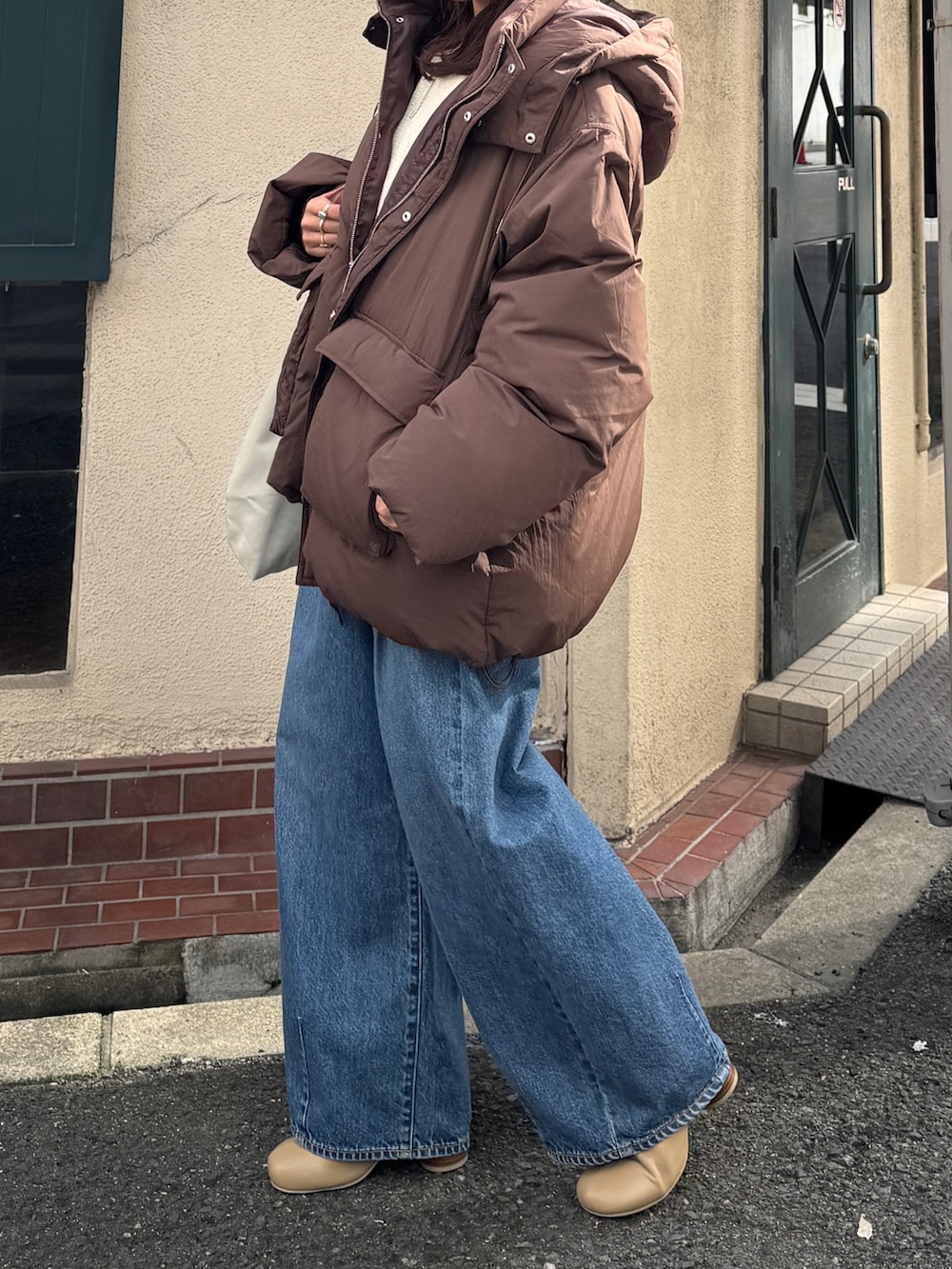 ブラウン系のダウンジャケット/コート、ホワイト系のニット/セーター、ブルー系のデニムパンツを着用したレディースの秋コーディネートの7枚目の写真