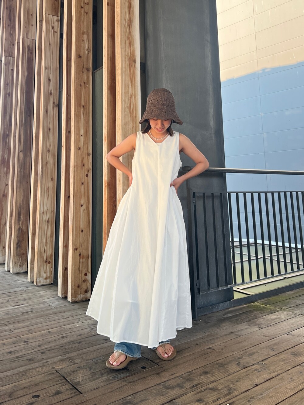 ホワイト系のワンピース、ブルー系のデニムパンツ、ブラウン系のハットを着用したレディースの夏コーディネートの6枚目の写真