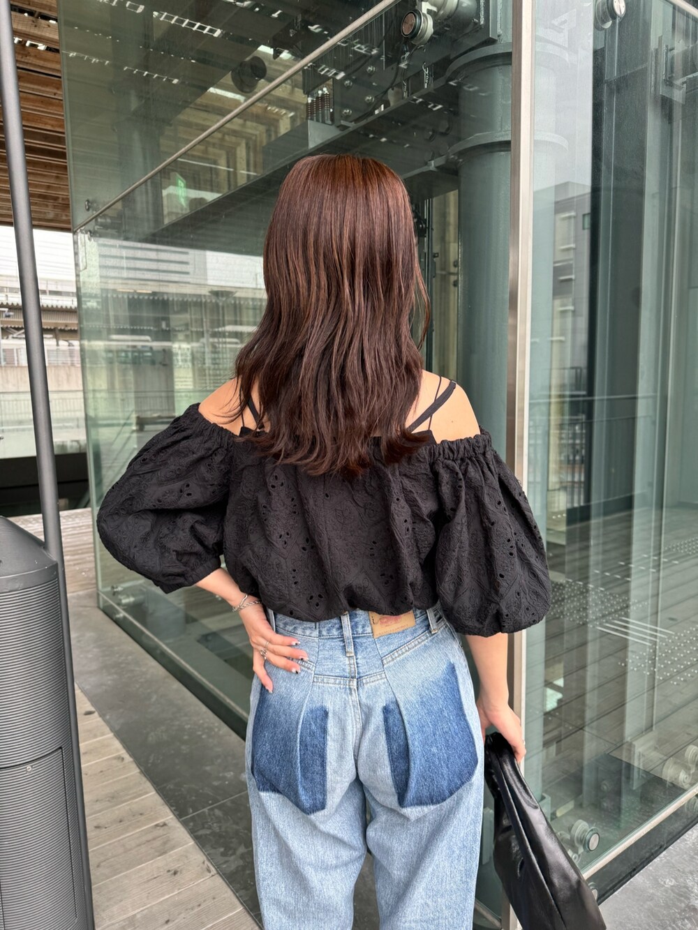 ブルー系のデニムパンツ、ブラック系のシャツ/ブラウス、ブラック系のハンドバッグを着用したレディースの春コーディネートの4枚目の写真