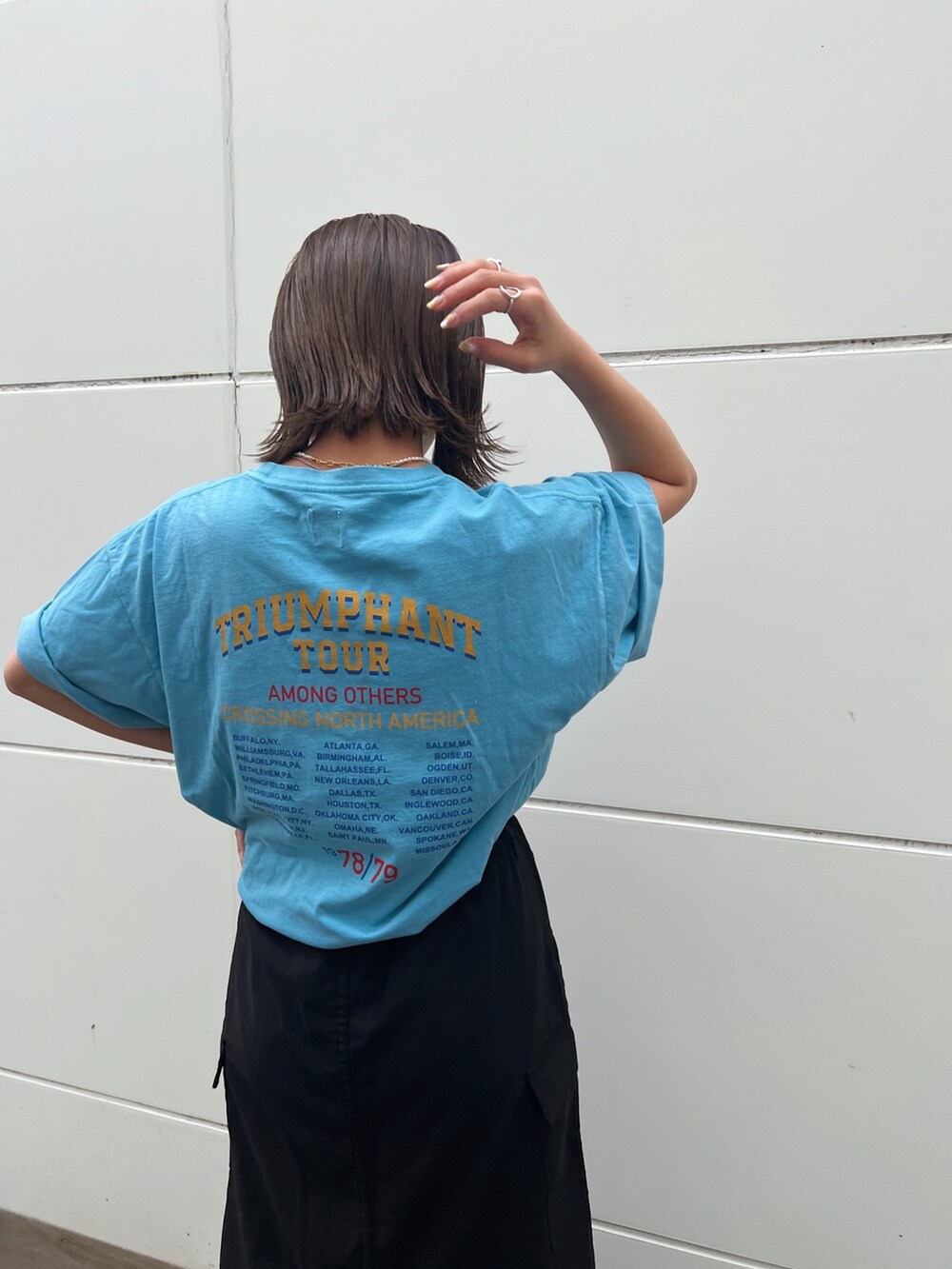 ブルー系のTシャツ/カットソー、ブラック系のスカート、ホワイト系のスニーカーを着用したレディースの春コーディネートの9枚目の写真