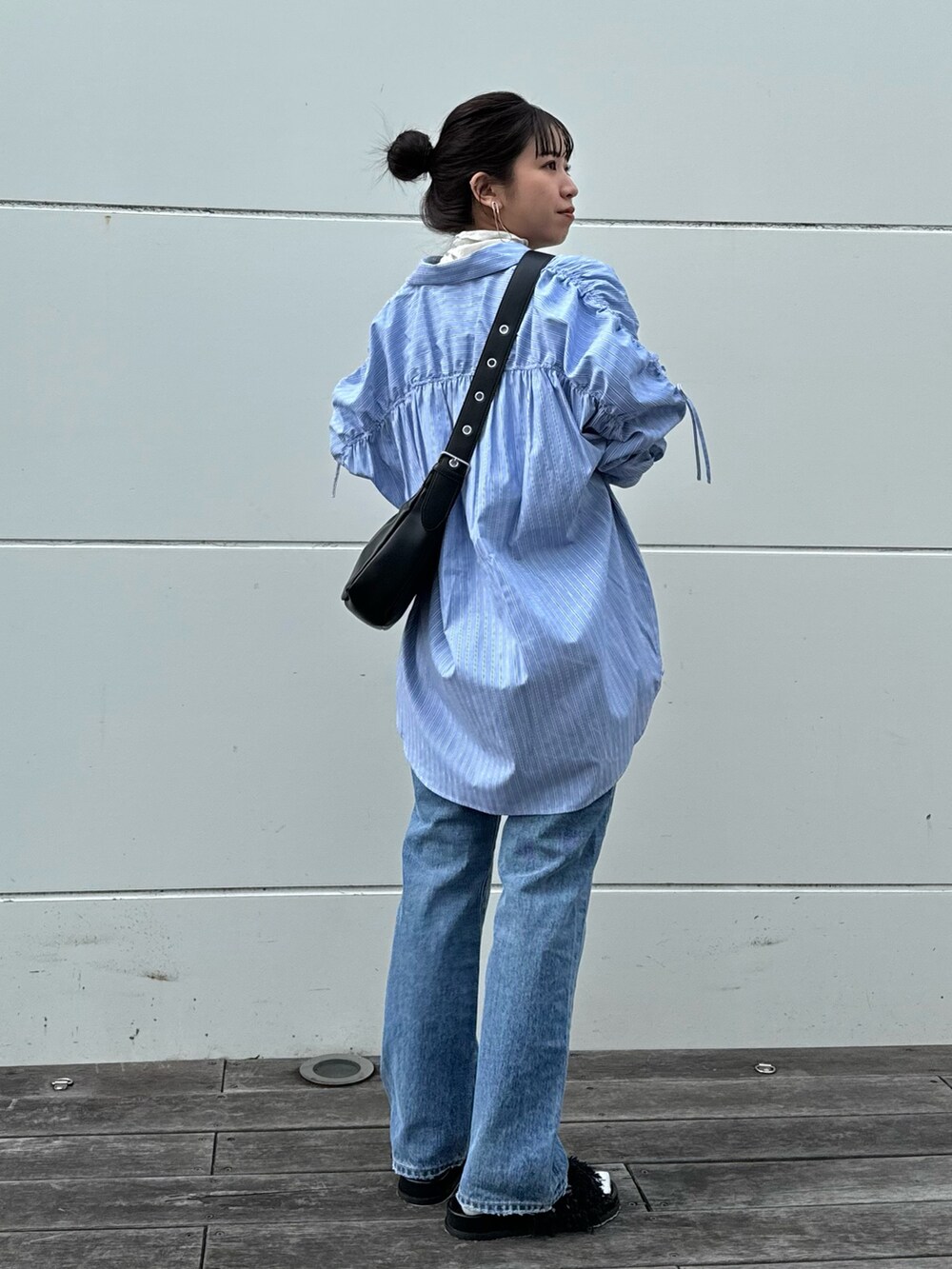ホワイト系のTシャツ/カットソー、ブルー系のデニムパンツ、ブラック系のショルダーバッグを着用したレディースの冬コーディネートの2枚目の写真