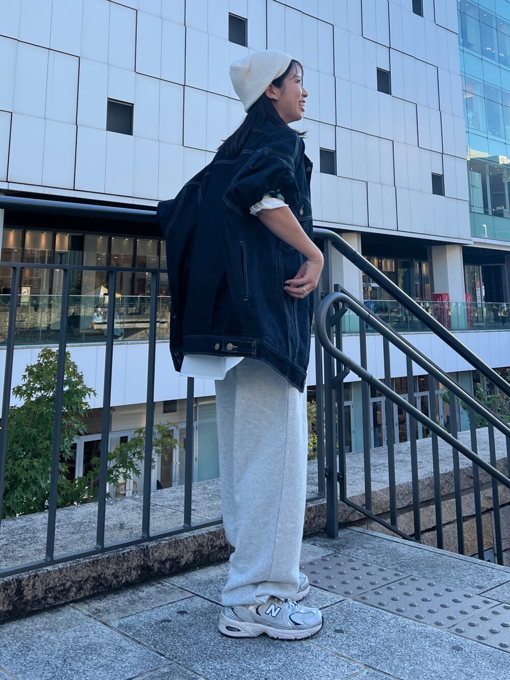 グレー系のスウェットパンツ、ブルー系のデニムジャケット、ブラック系のキャミソールを着用したレディースの秋コーディネートの2枚目の写真