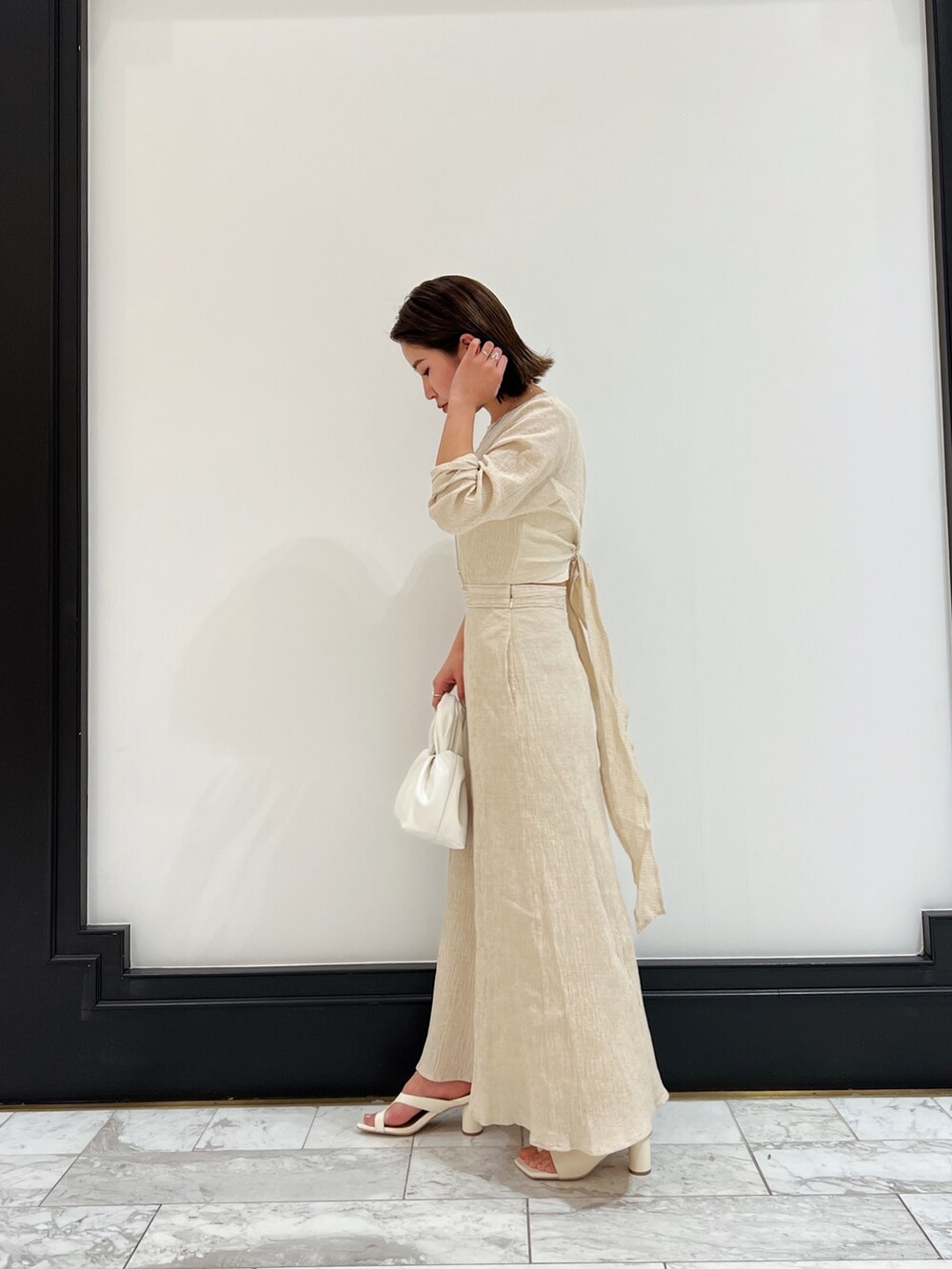 ホワイト系のベスト、ホワイト系のワンピース、ホワイト系のハンドバッグを着用したレディースの春コーディネートの4枚目の写真