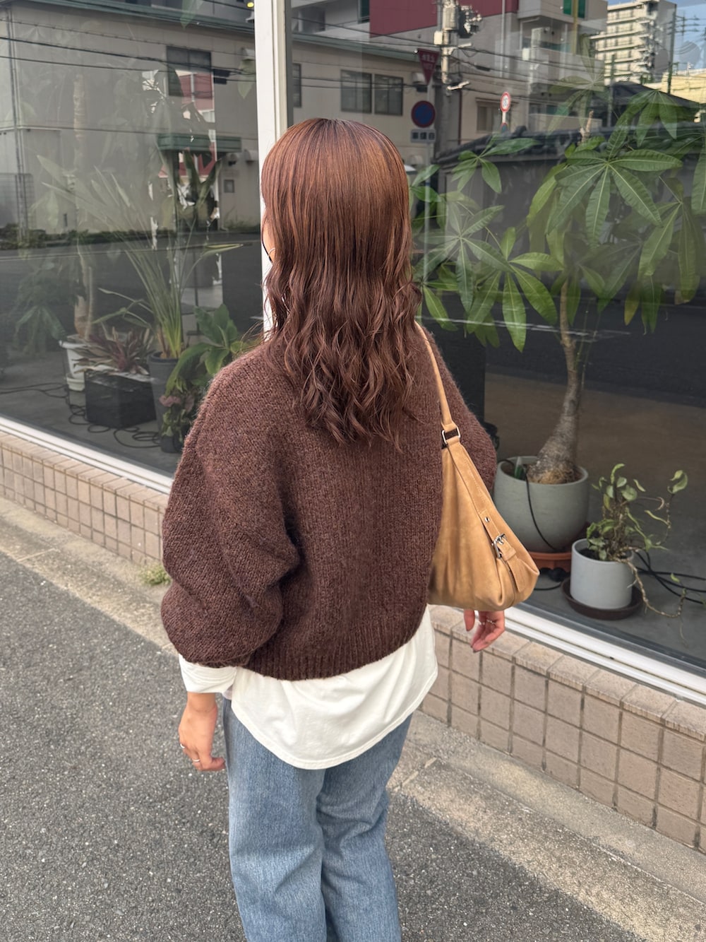 ホワイト系のTシャツ/カットソー、ブラウン系のニット/セーター、ブルー系のデニムパンツを着用したレディースの秋コーディネートの6枚目の写真