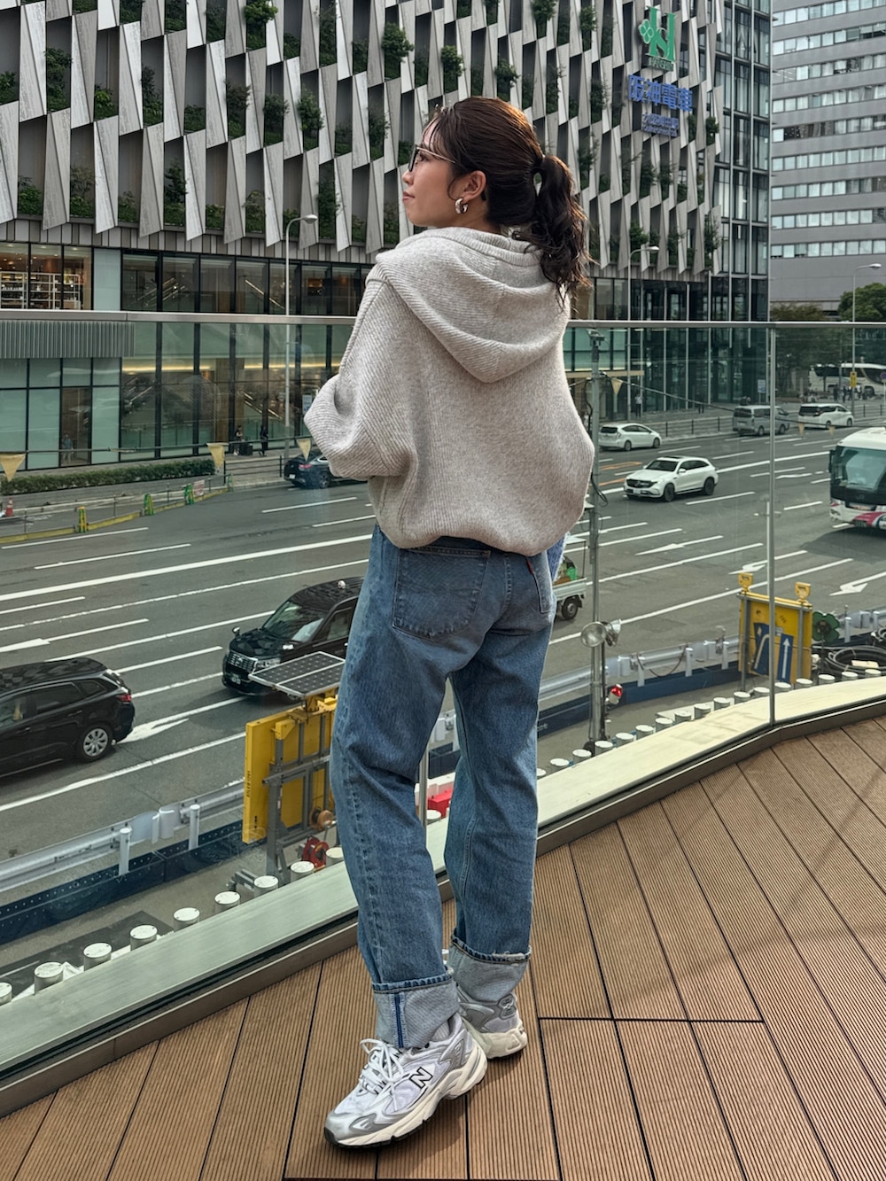 ブルー系のハンドバッグ、グレー系のニット/セーター、ブルー系のデニムパンツを着用したレディースの秋コーディネートの4枚目の写真