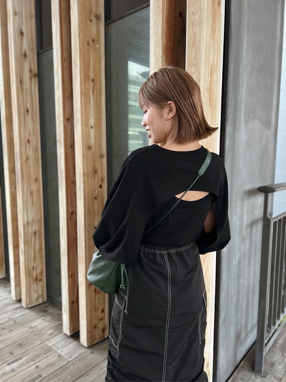 グリーン系のハンドバッグ、ブラック系のTシャツ/カットソー、ブラック系のスカートを着用したレディースの夏コーディネートの6枚目の写真
