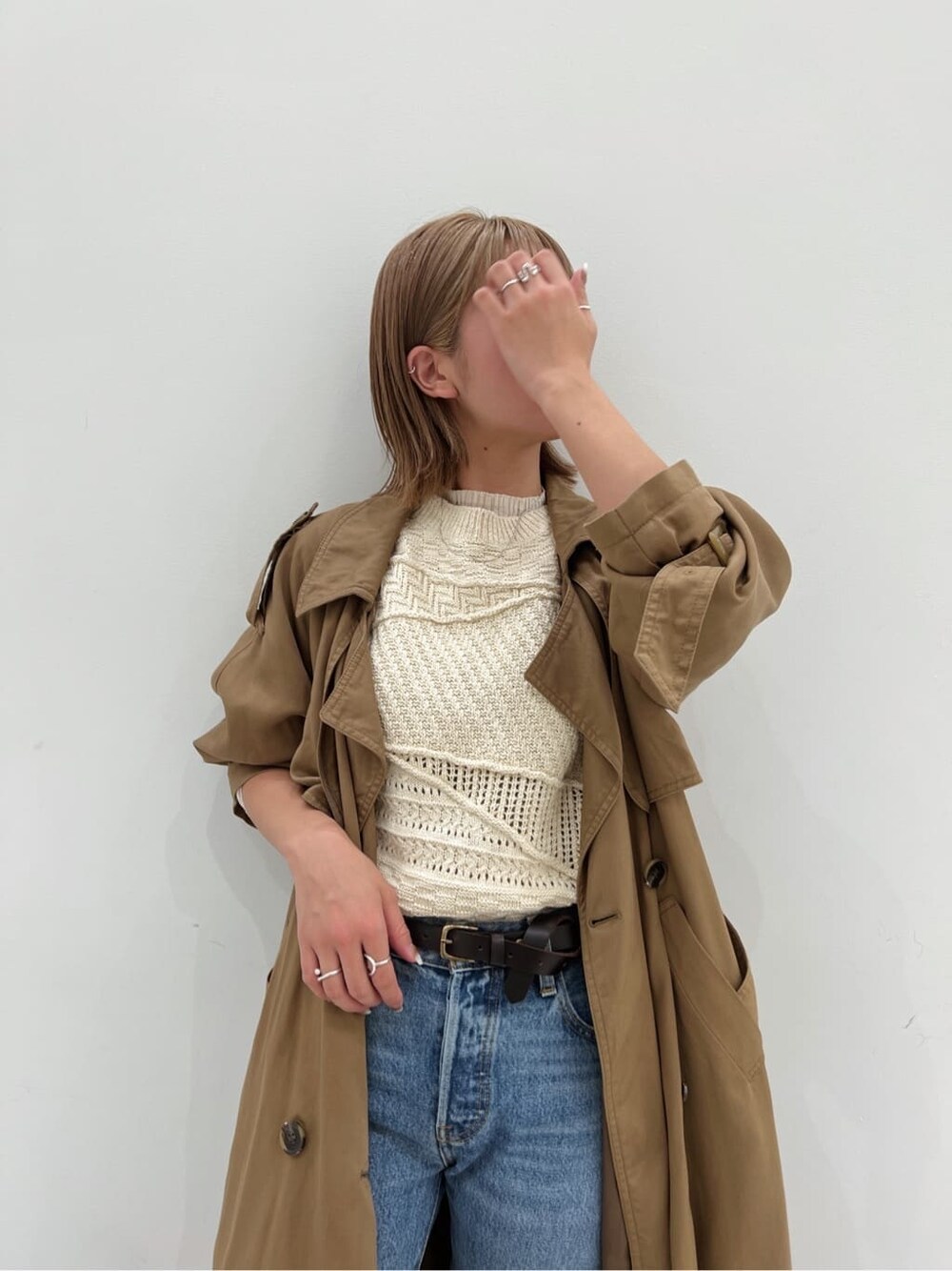 ブラウン系のトレンチコート、ブラック系のブーツ、ホワイト系のニット/セーターを着用したレディースの夏コーディネートの6枚目の写真