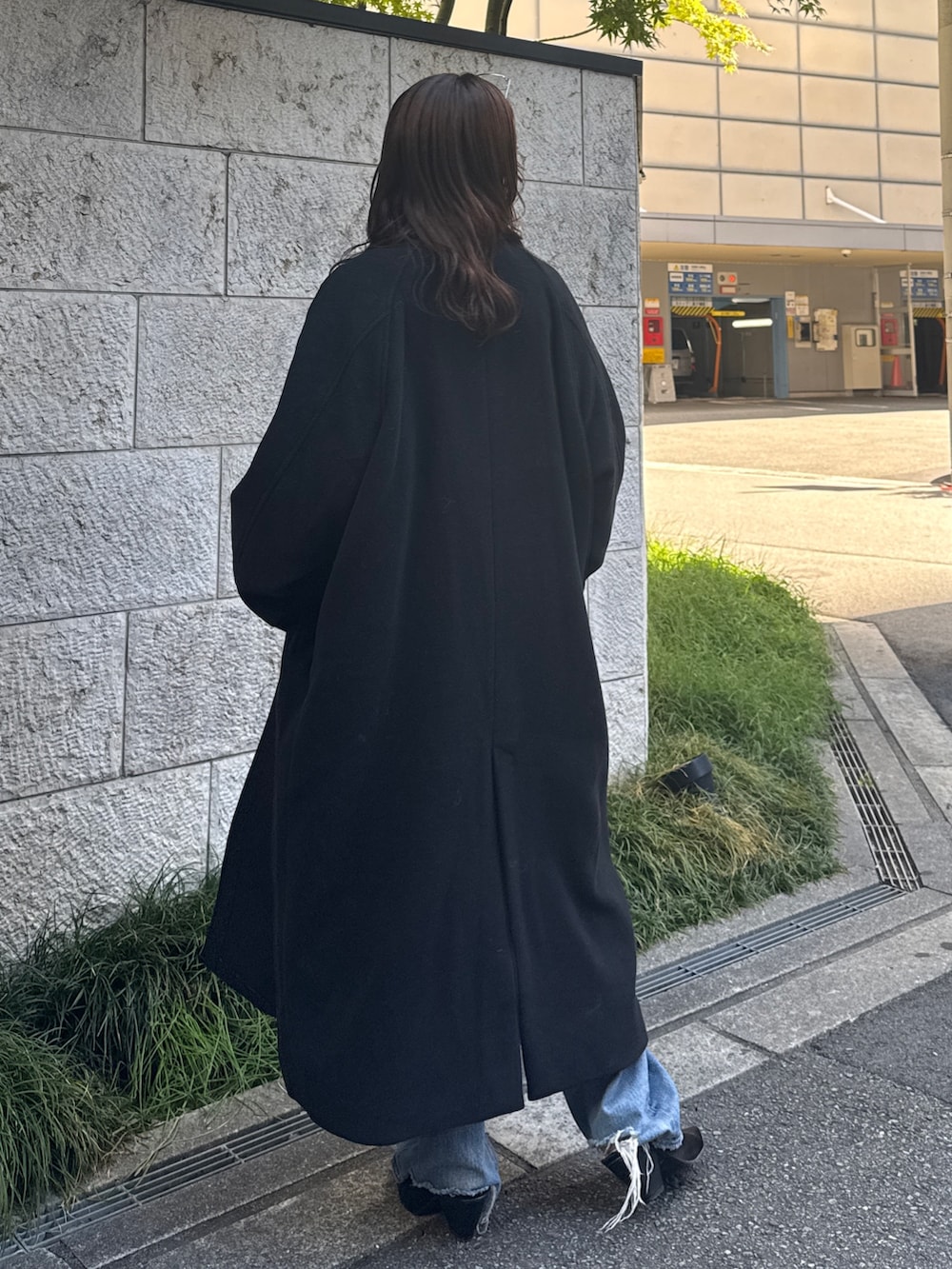 ブルー系のデニムパンツ、ブルー系のニット/セーター、ブラック系のチェスターコートを着用したレディースの秋コーディネートの4枚目の写真