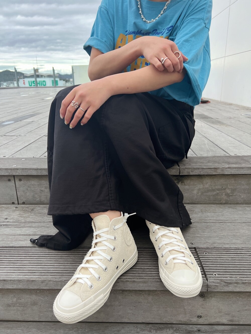 ブルー系のTシャツ/カットソー、ブラック系のスカート、ホワイト系のスニーカーを着用したレディースの春コーディネートの10枚目の写真