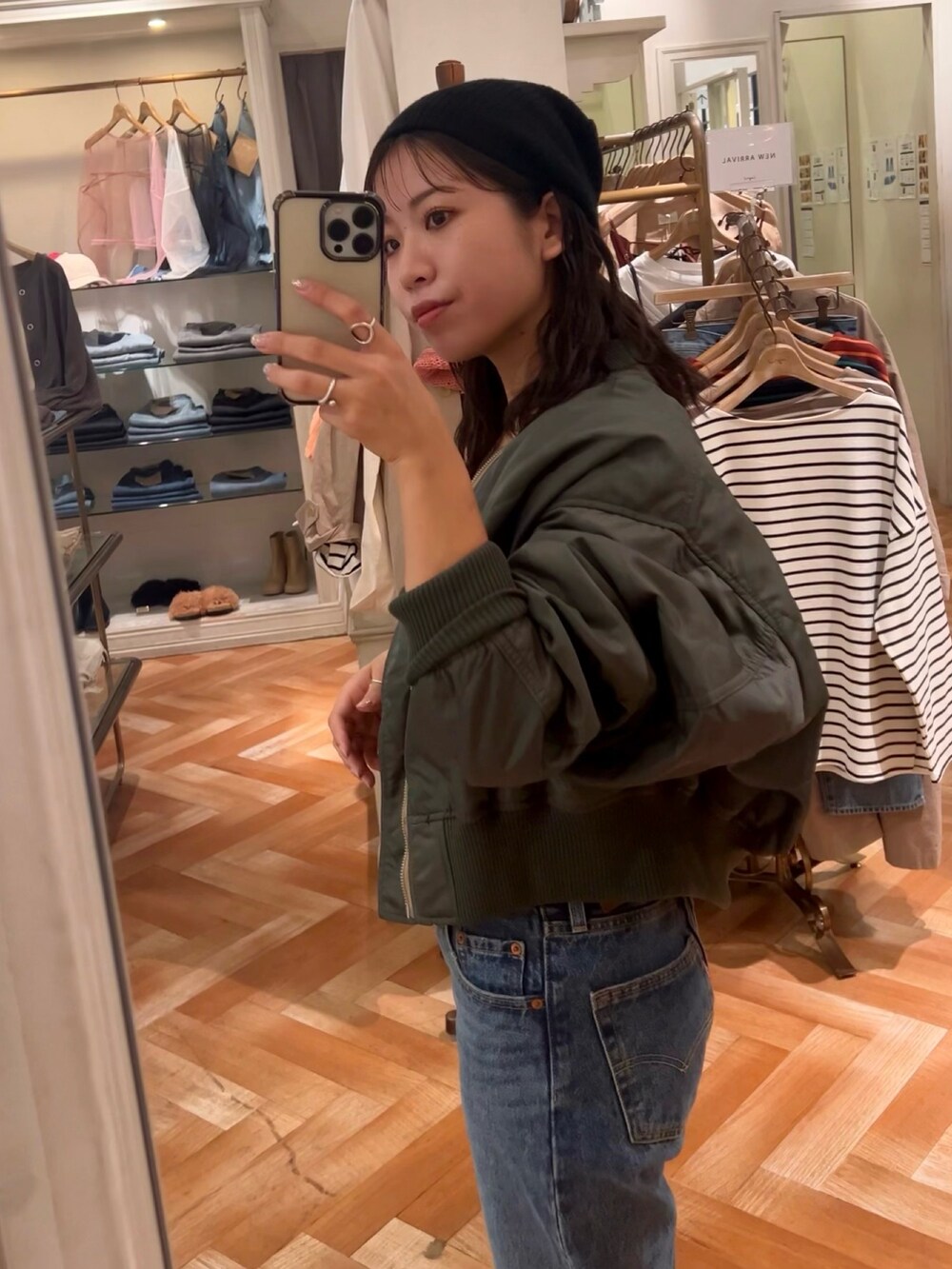 ブラック系のキャミソール、ブルー系のデニムパンツ、グリーン系のブルゾンを着用したレディースの秋コーディネートの2枚目の写真