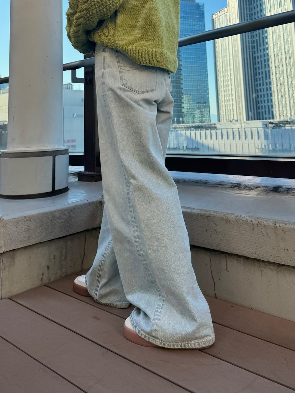 グリーン系のニット/セーター、ホワイト系のTシャツ/カットソー、ブルー系のデニムパンツを着用したレディースの冬コーディネートの10枚目の写真