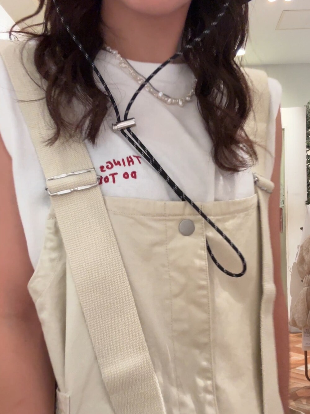 ベージュ系のサロペット/オーバーオール、ホワイト系のTシャツ/カットソー、ブラック系のサンダルを着用したレディースの夏コーディネートの7枚目の写真
