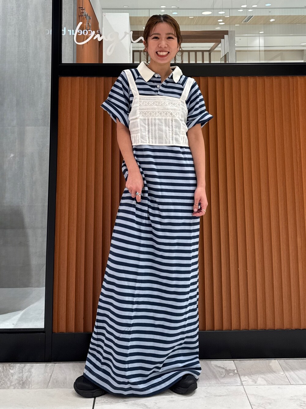 ホワイト系のキャミソール、ブルー系のワンピース、ブラック系のスニーカーを着用したレディースの春コーディネートの6枚目の写真