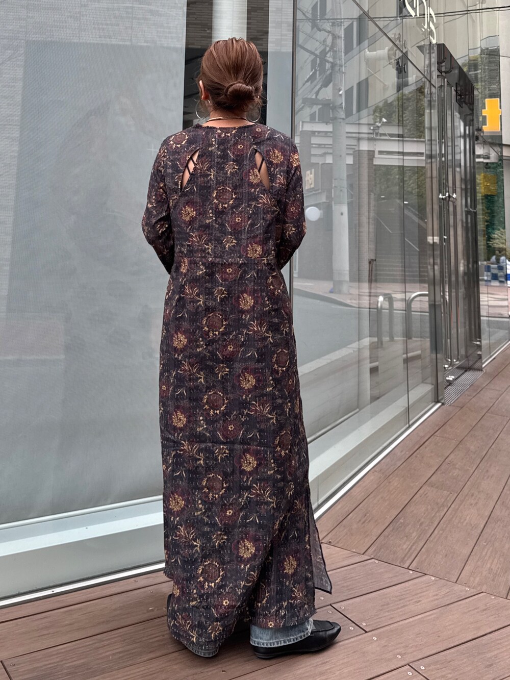 ブラック系のワンピース、ブルー系のデニムパンツ、ブラウン系のネックレスを着用したレディースの冬コーディネートの4枚目の写真