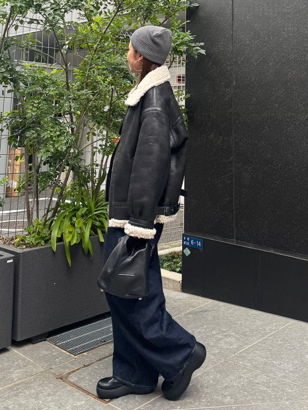 ブラック系のブルゾン、ブルー系のデニムパンツ、グレー系のニット/セーターを着用したレディースの秋コーディネートの5枚目の写真