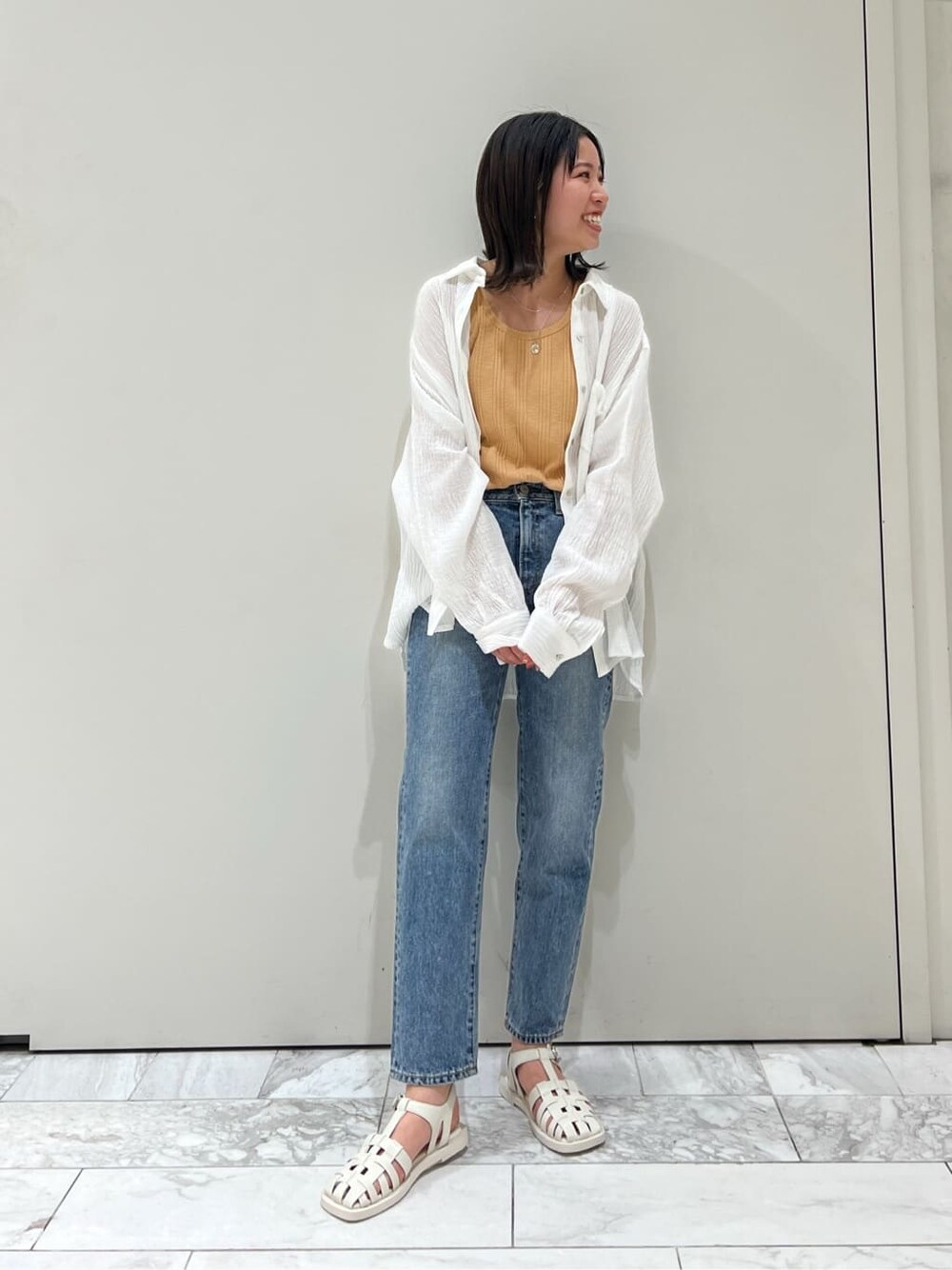 ブルー系のデニムパンツ、オレンジ系のタンクトップ、ホワイト系のシャツ/ブラウスを着用したレディースの春コーディネートの3枚目の写真