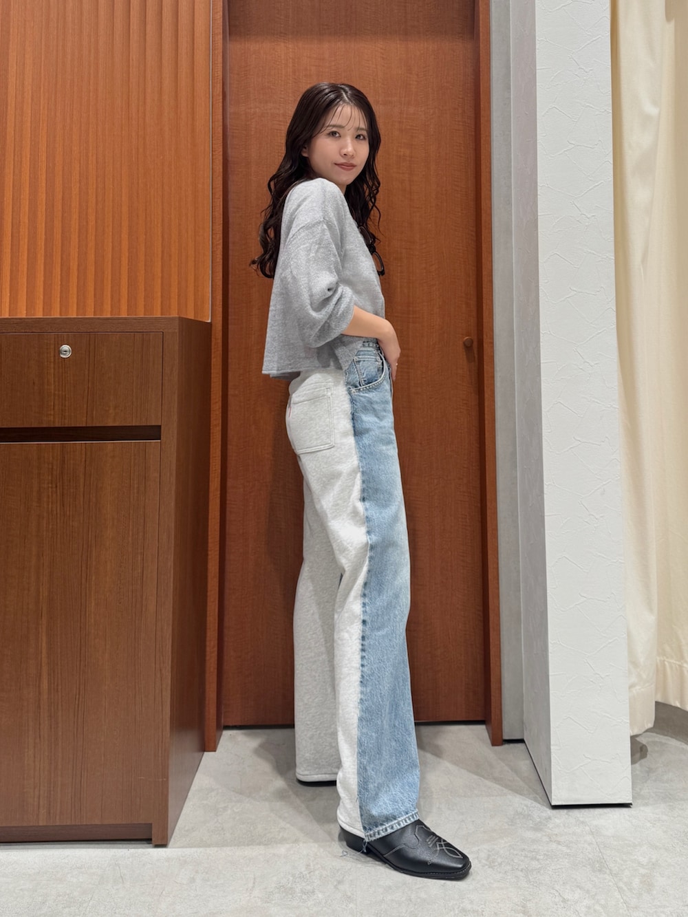 ブルー系のデニムパンツ、グレー系のニット/セーター、ホワイト系のTシャツ/カットソーを着用したレディースの秋コーディネートの2枚目の写真