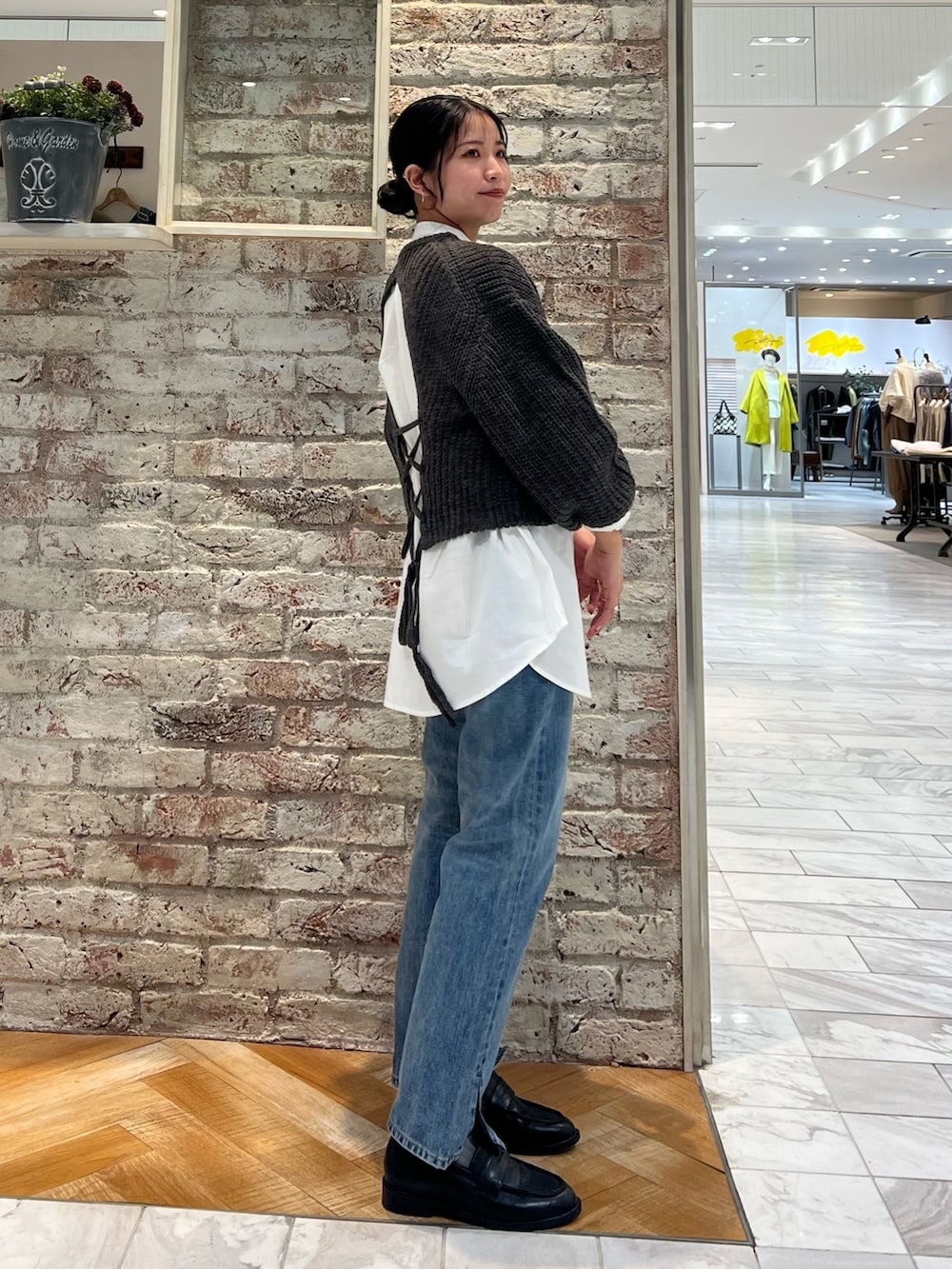 グレー系のニット/セーター、ブルー系のデニムパンツ、ブラック系のローファーを着用したレディースの秋コーディネートの2枚目の写真