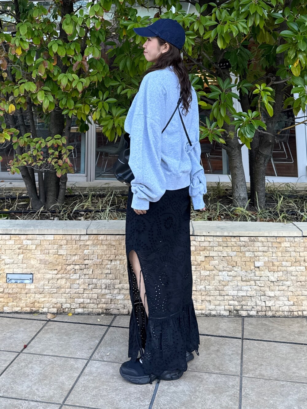 ブラック系のスカート、グレー系のスウェット、ブラック系のスニーカーを着用したレディースの冬コーディネートの8枚目の写真