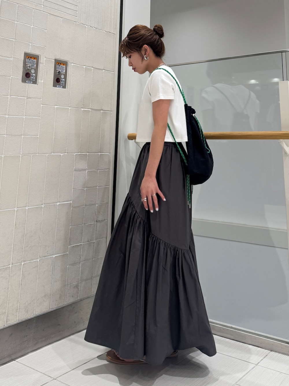 グレー系のスカート、シルバー系のサンダル、ホワイト系のTシャツ/カットソーを着用したレディースの春コーディネートの3枚目の写真