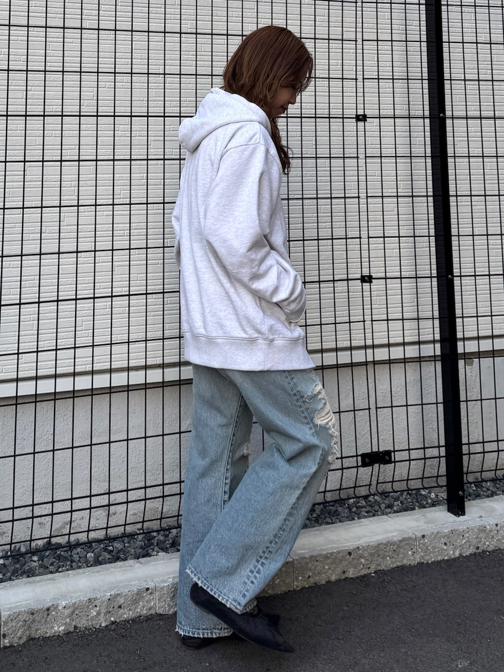 グレー系のパーカー、ブルー系のデニムパンツ、ブラック系のパンプスを着用したレディースの春コーディネートの2枚目の写真