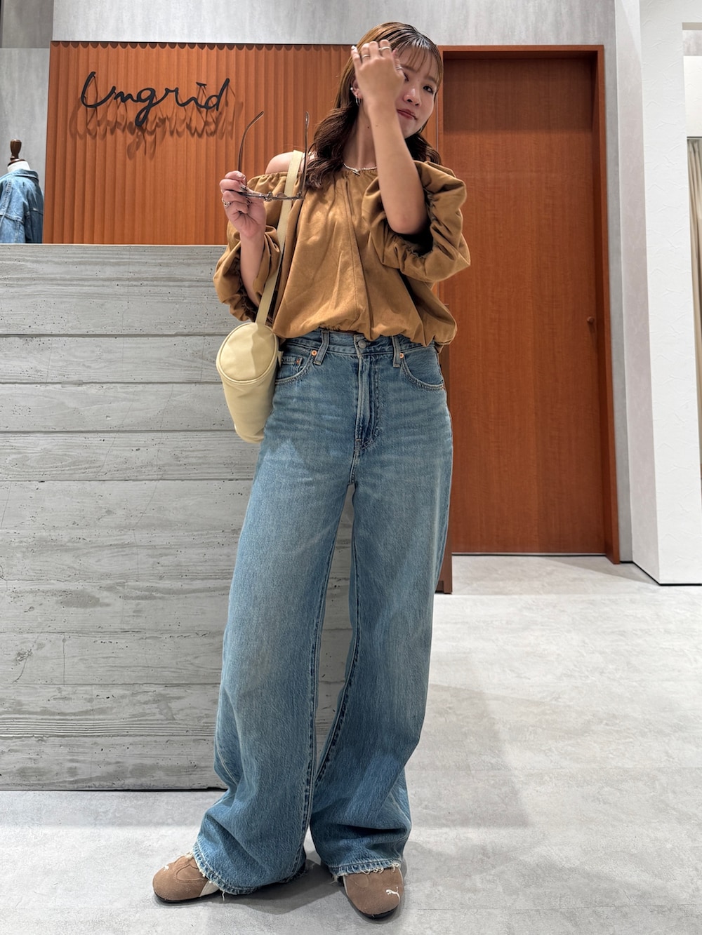 ブルー系のデニムパンツ、イエロー系のシャツ/ブラウス、ブラウン系のサングラスを着用したレディースの夏コーディネートの2枚目の写真