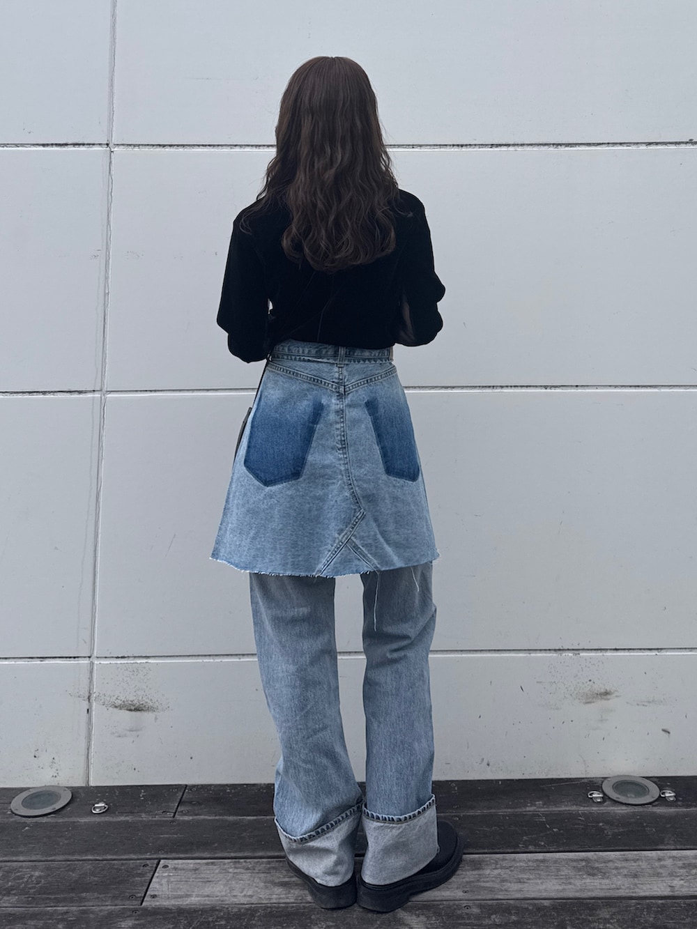 ブラック系のTシャツ/カットソー、ブルー系のスカート、ブルー系のデニムパンツを着用したレディースの冬コーディネートの5枚目の写真