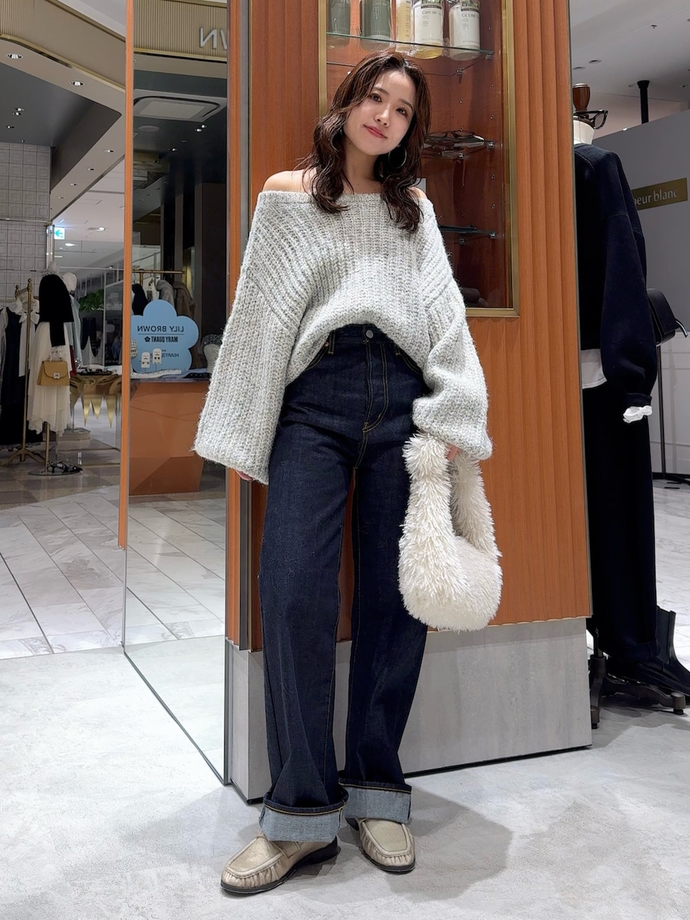 グレー系のニット/セーター、ブルー系のデニムパンツ、ホワイト系のハンドバッグを着用したレディースの冬コーディネートの7枚目の写真