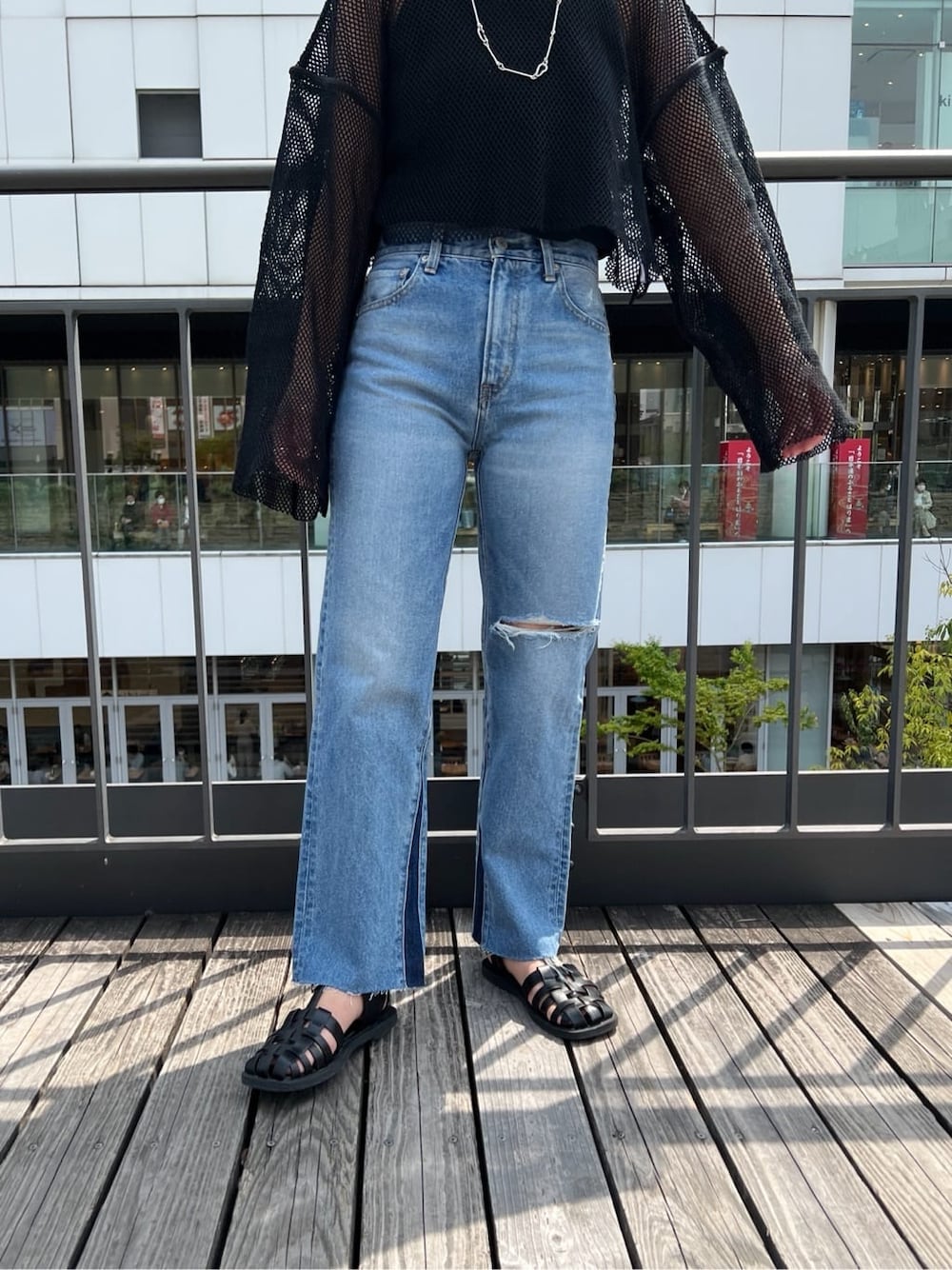 ブラック系のサンダル、ブルー系のデニムパンツ、ブラック系のTシャツ/カットソーを着用したレディースの春コーディネートの6枚目の写真