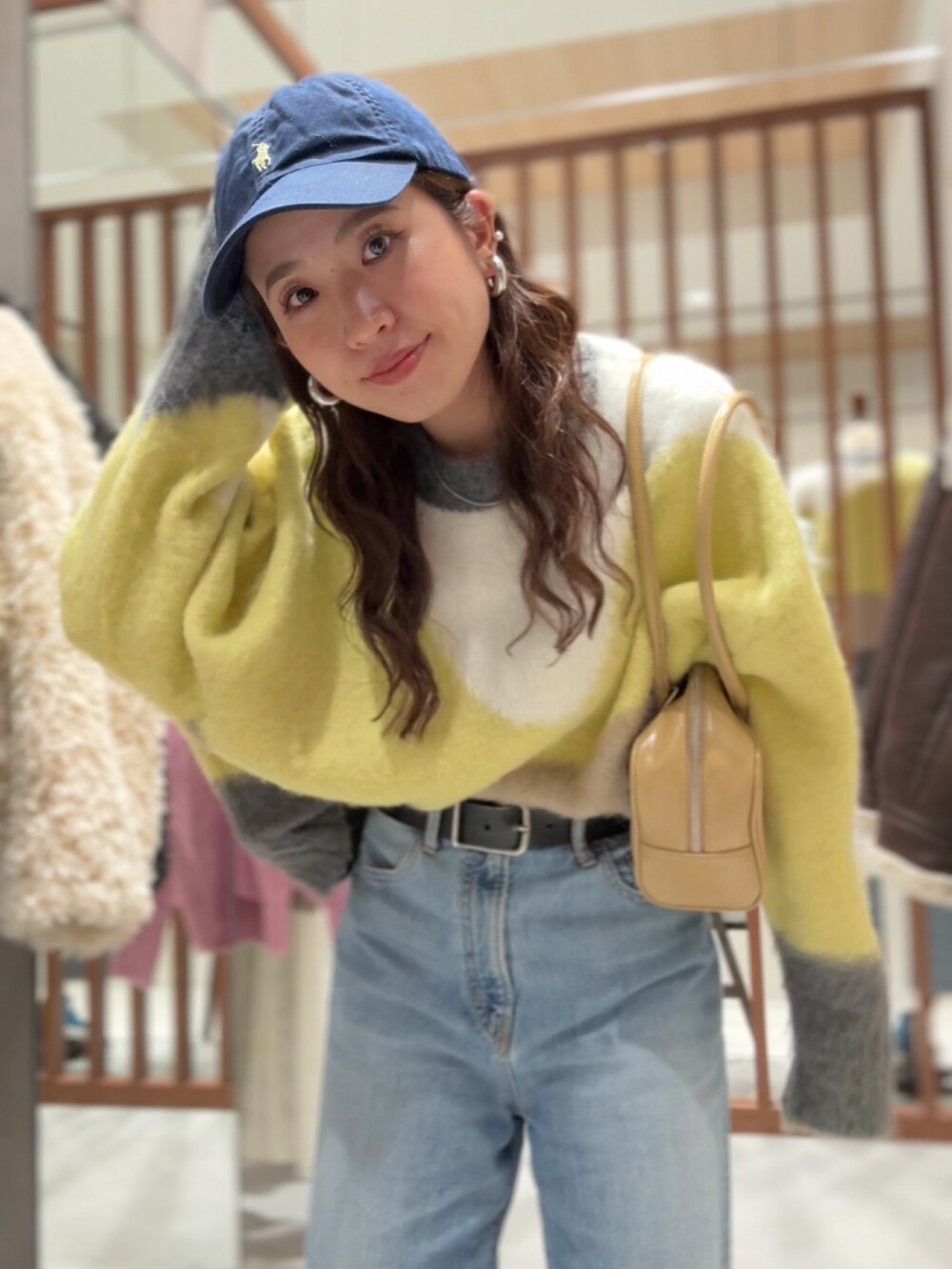 グリーン系のニット/セーター、ブルー系のデニムパンツ、ベージュ系のハンドバッグを着用したレディースの秋コーディネートの8枚目の写真