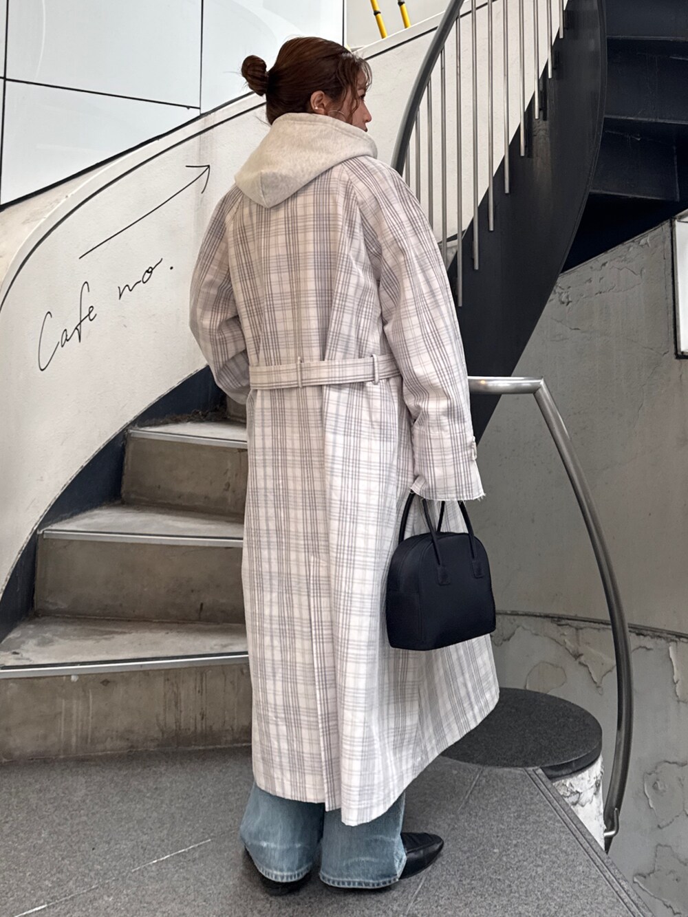 その他のステンカラーコート、ブラック系のボストンバッグ、ホワイト系のパーカーを着用したレディースの冬コーディネートの4枚目の写真