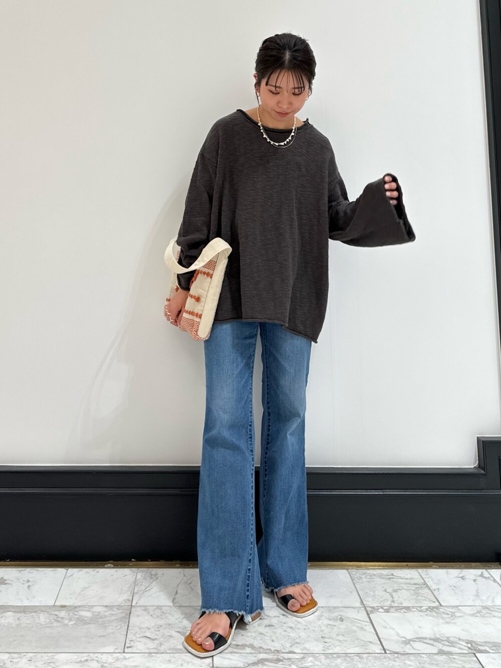 グレー系のニット/セーター、ブルー系のデニムパンツ、ブラック系のサンダルを着用したレディースの春コーディネートの9枚目の写真