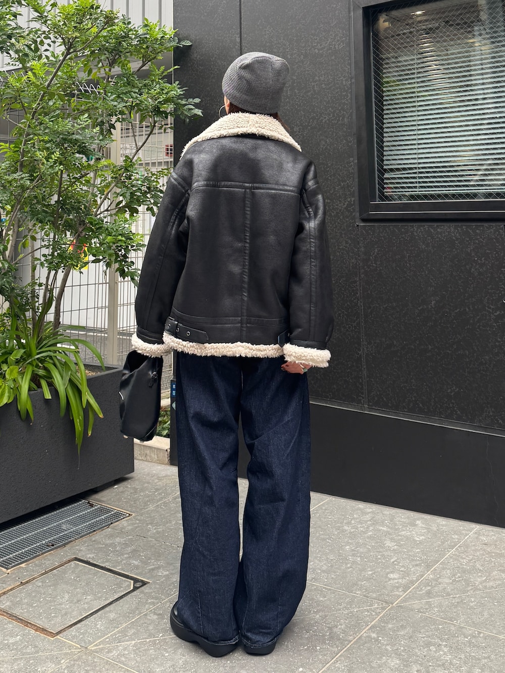 ブラック系のブルゾン、ブルー系のデニムパンツ、グレー系のニット/セーターを着用したレディースの秋コーディネートの4枚目の写真