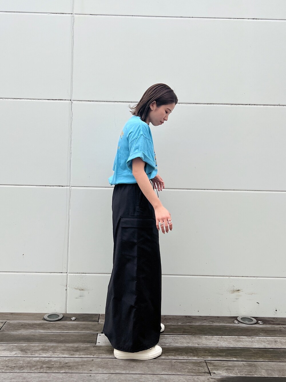 ブルー系のTシャツ/カットソー、ブラック系のスカート、ホワイト系のスニーカーを着用したレディースの春コーディネートの5枚目の写真