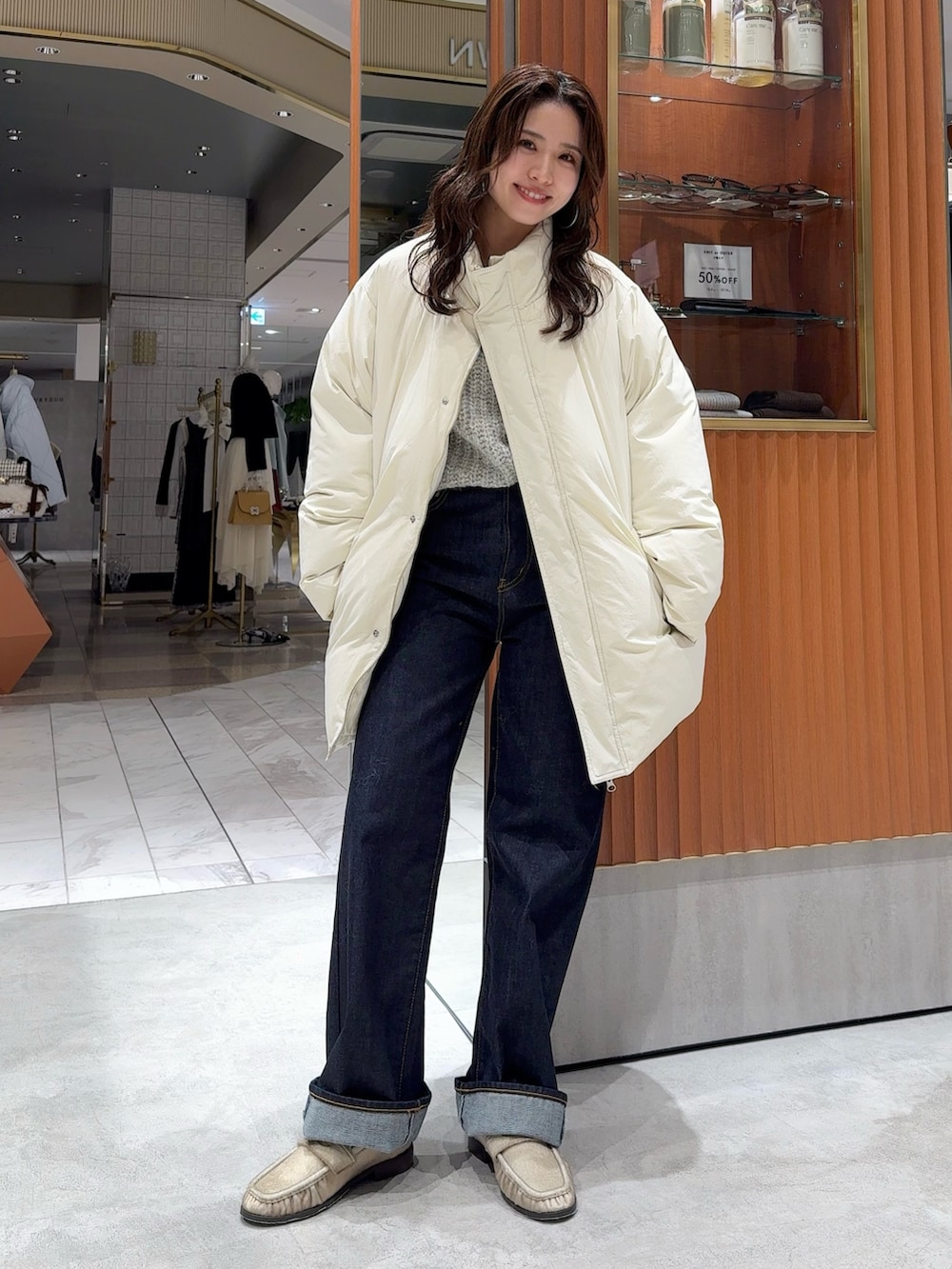 ホワイト系のダウンジャケット/コート、グレー系のニット/セーター、ブルー系のデニムパンツを着用したレディースの冬コーディネートの6枚目の写真