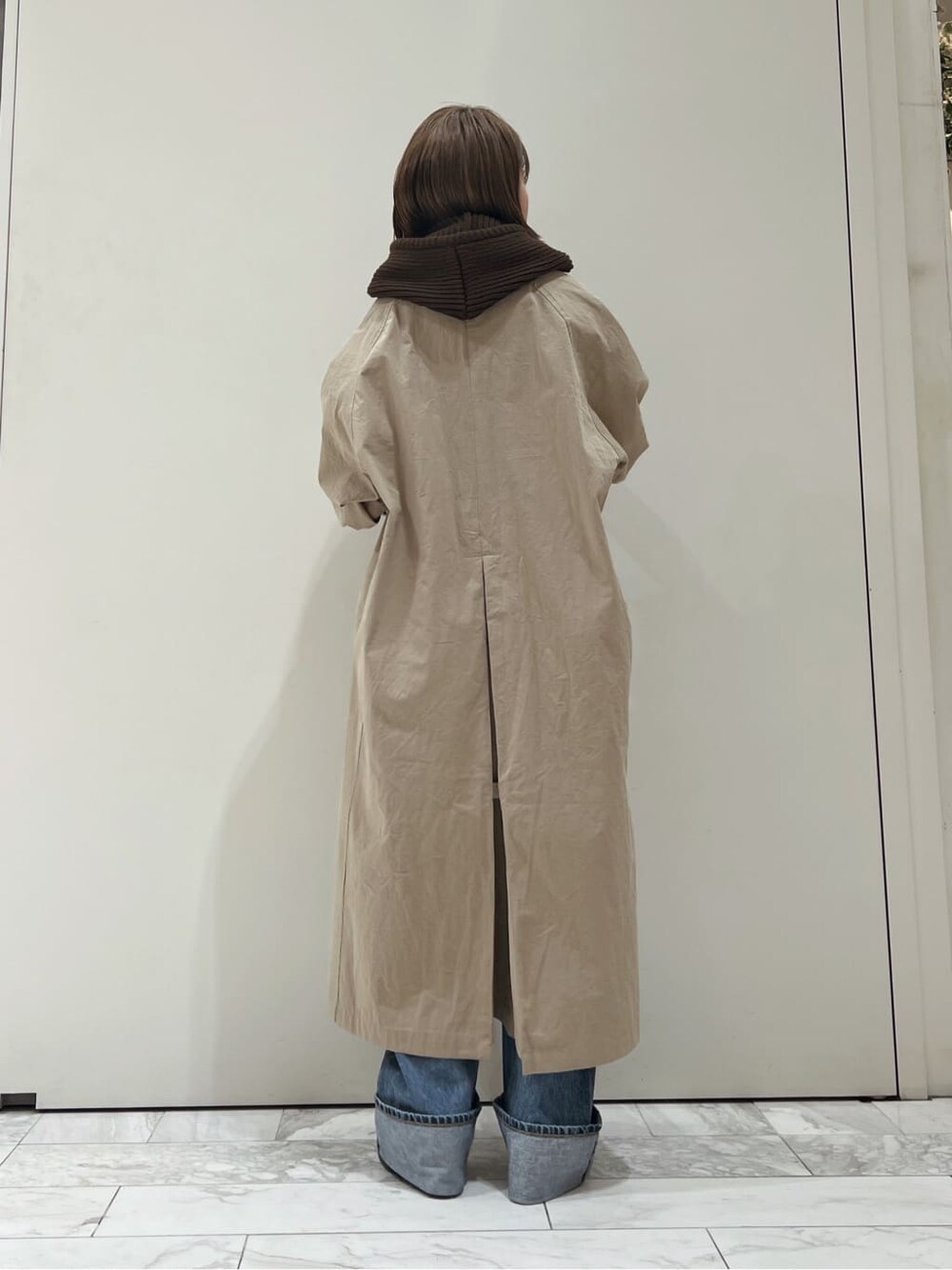 ベージュ系のステンカラーコート、ブラック系のブーツ、ブルー系のデニムパンツを着用したレディースの秋コーディネートの4枚目の写真