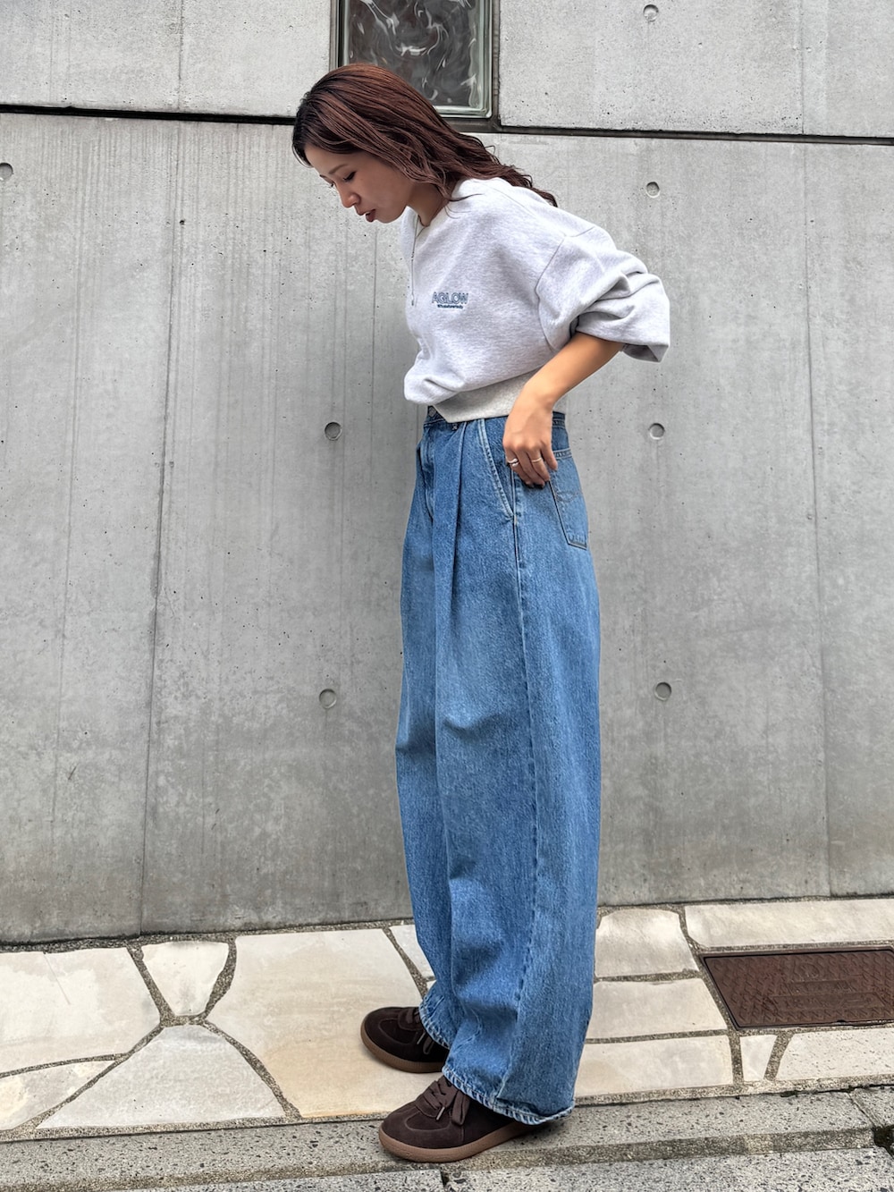 ブルー系のデニムパンツ、グレー系のスウェット、ブラウン系のスニーカーを着用したレディースの秋コーディネートの5枚目の写真