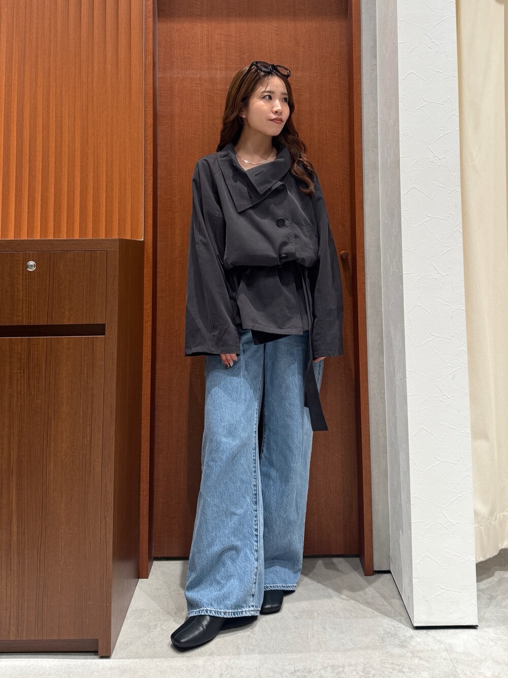 グレー系のトレンチコート、ブルー系のデニムパンツ、シルバー系のネックレスを着用したレディースの秋コーディネートの5枚目の写真