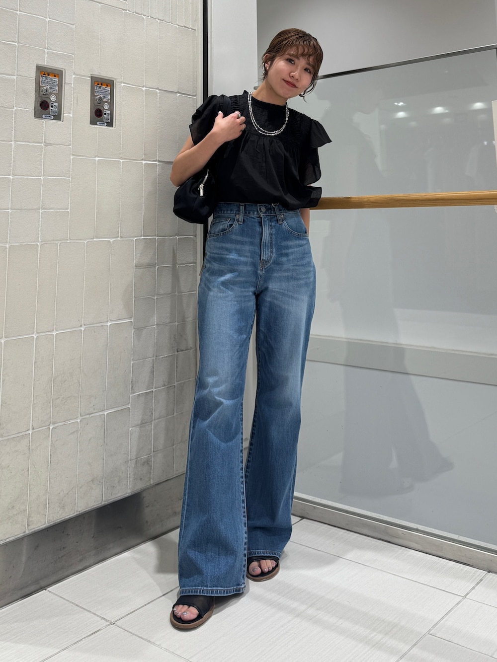 ブルー系のデニムパンツ、ブラック系のシャツ/ブラウス、ブラック系のハンドバッグを着用したレディースの春コーディネートの2枚目の写真