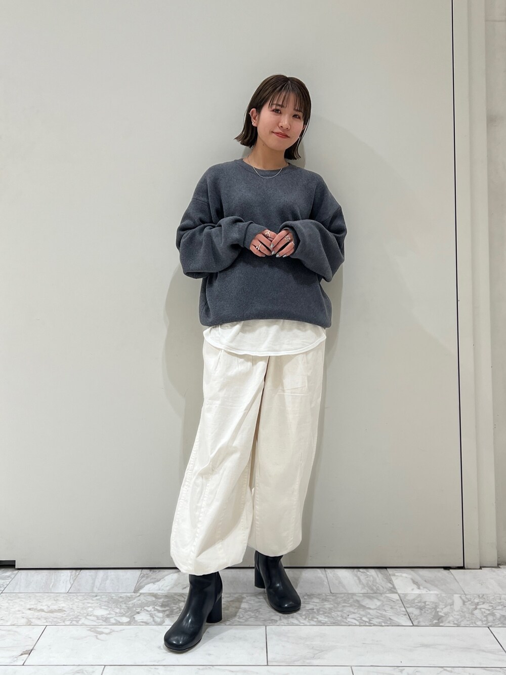 グレー系のニット/セーター、ホワイト系のTシャツ/カットソー、ホワイト系のその他パンツを着用したレディースの冬コーディネートの2枚目の写真